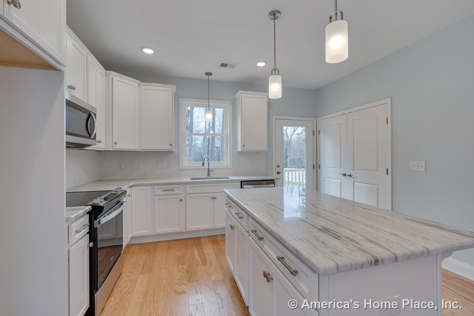 White shaker cabinets and marble island countertop with stainless steel built-in appliances, tile backsplash, hardwood flooring, recessed and pendant lighting, window, and double