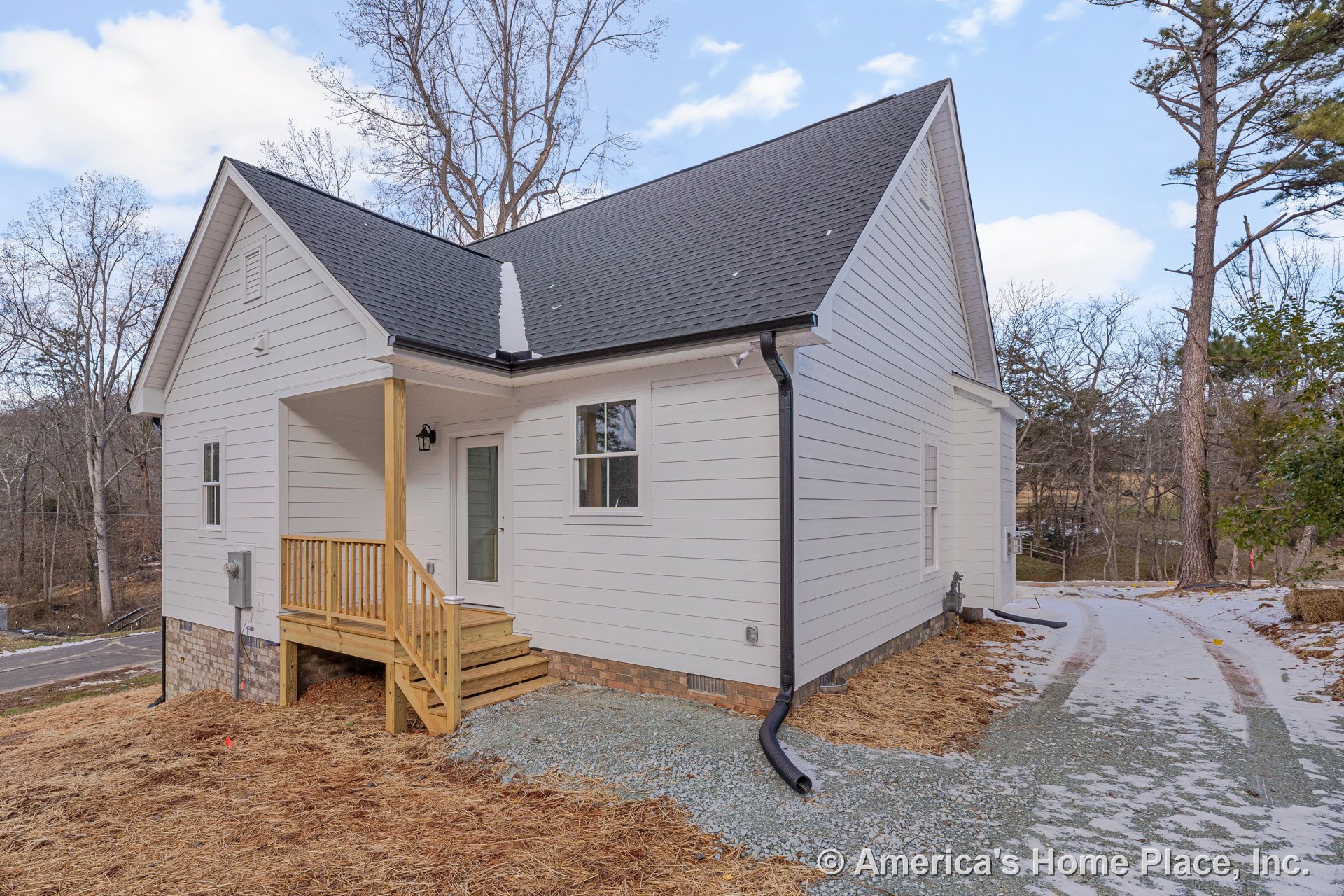 White horizontal siding and black shingle roof with a covered entry porch featuring wood railings, single exterior door, brick foundation, exterior lighting, steps, driveway, and