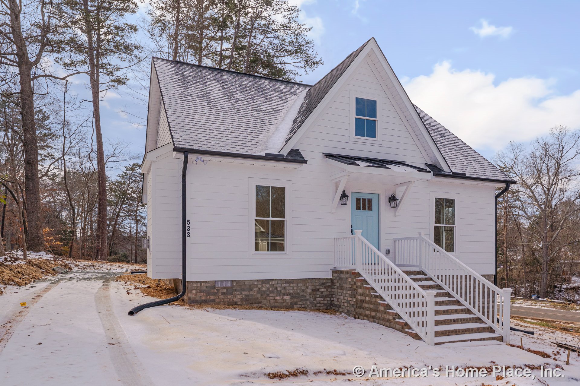 White horizontal siding exterior with gabled roof, covered front porch featuring brick foundation and steps, double-hung windows, blue front door, white trim, porch railing