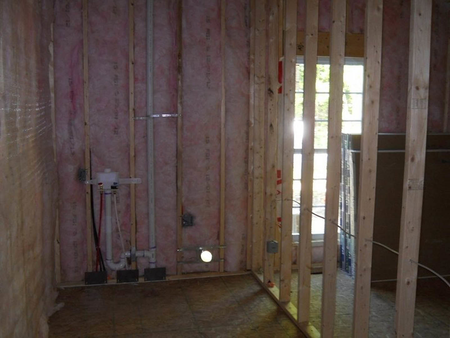 Laundry room with plaster walls, wood floor, ceiling fixture, and large window letting in natural light