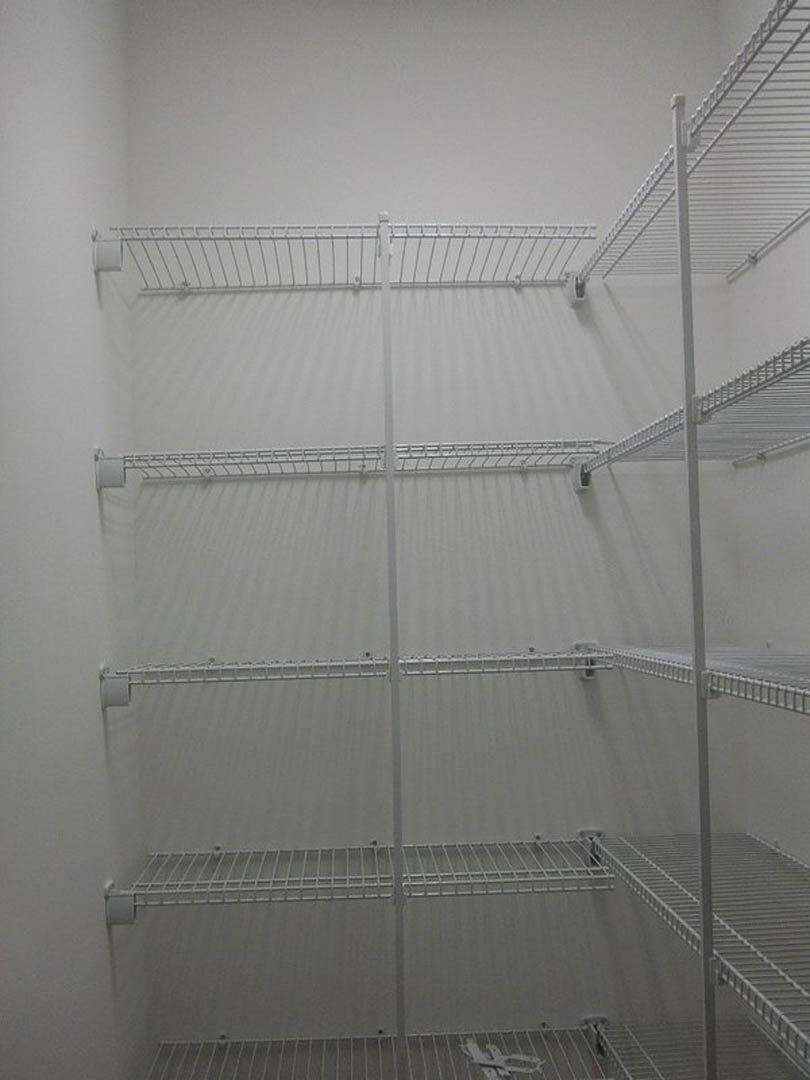 White empty closet with built-in metal shelving and smooth walls