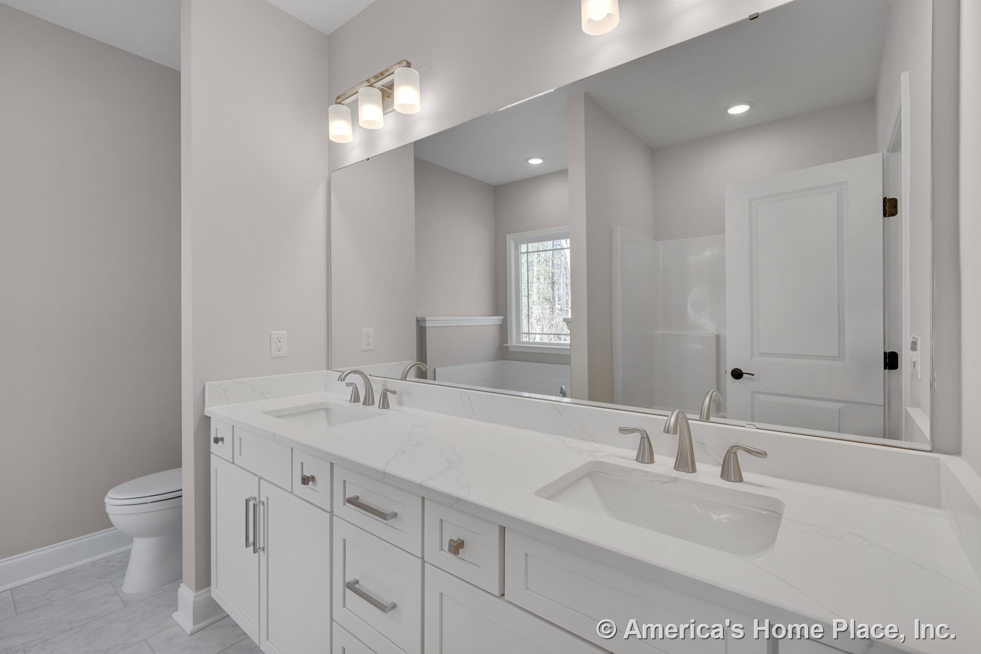 Double vanity with white shaker cabinets, marble-look countertops, undermount sinks, chrome faucets, large wall mirror, built-in lighting fixture, tile flooring, window, and