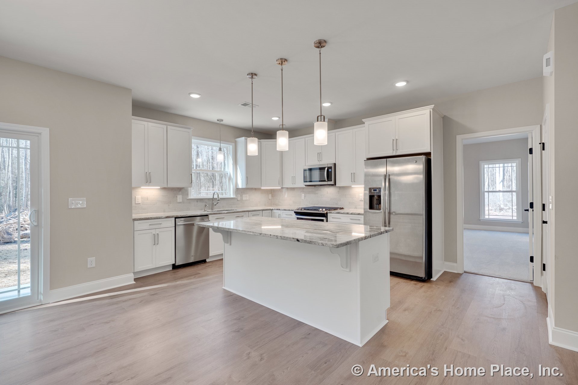 White shaker kitchen cabinets, stainless steel double-door refrigerator, built-in microwave, dishwasher, large central island with marble-look countertops, pendant lighting, tile