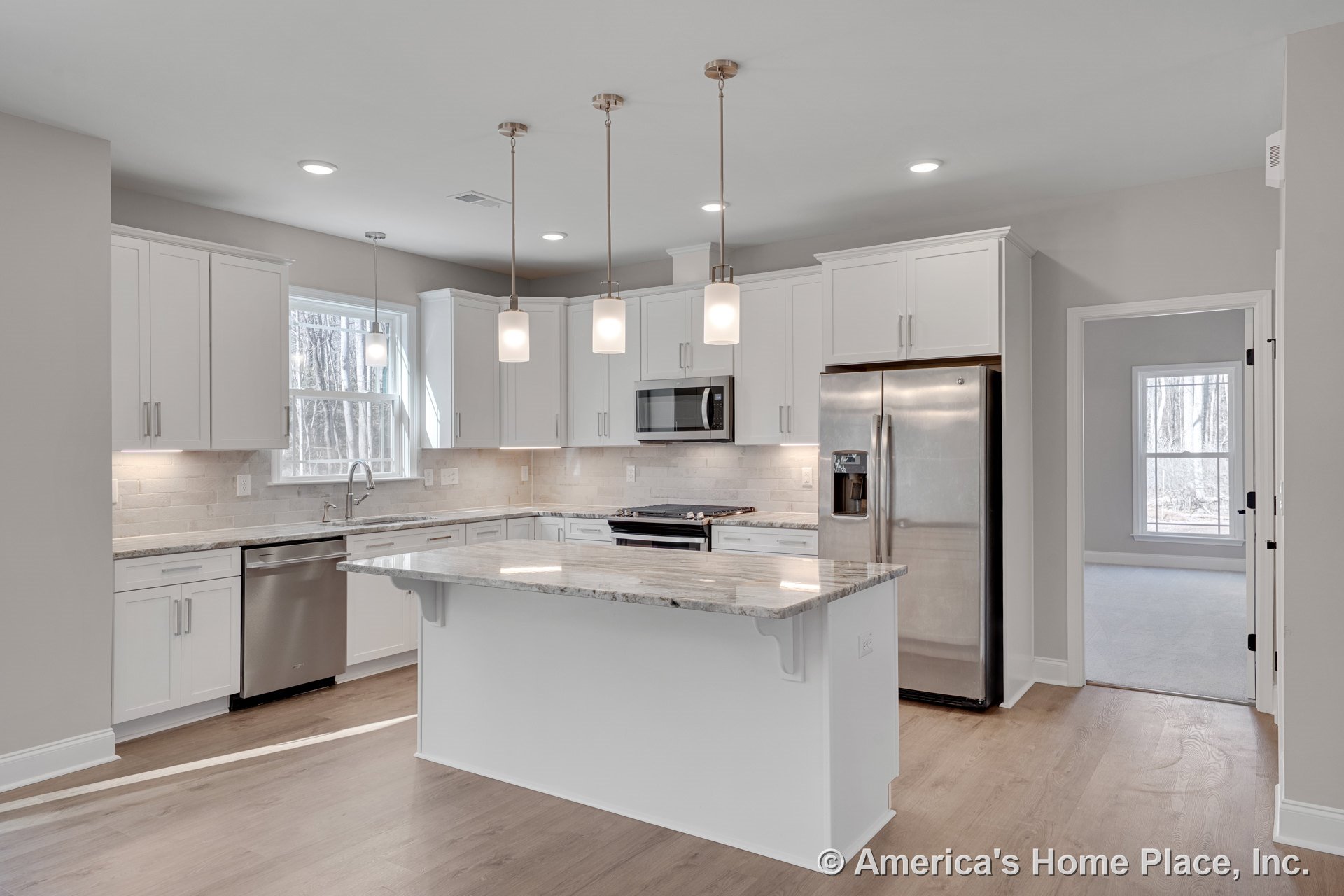 White shaker cabinets, central stone countertop island, stainless steel refrigerator, tile backsplash, pendant and recessed lighting, wood flooring, window with trim, open kitchen