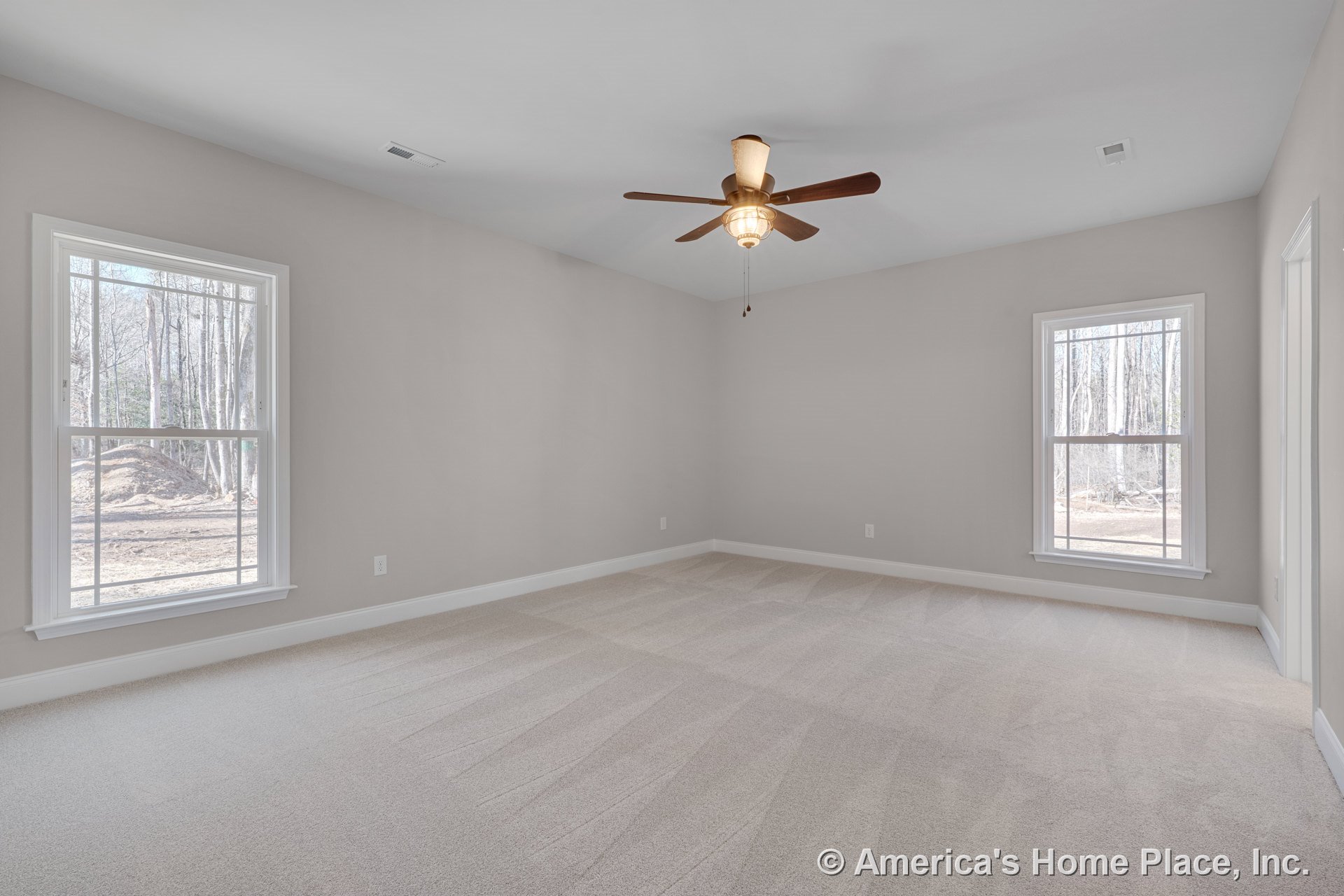 Spacious bedroom with light carpet flooring, vaulted ceiling, ceiling fan with built-in lighting, two large double-hung windows, neutral wall color, and white baseboard trim.