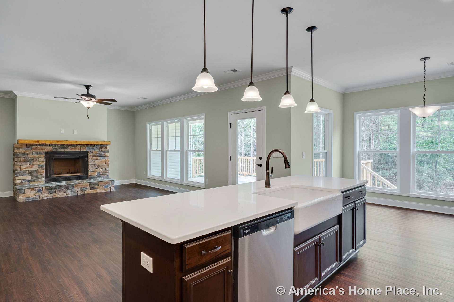 Open kitchen and living area with stone fireplace and wood mantel, dark wood cabinetry, white quartz countertops, central island featuring farmhouse sink, pendant lighting