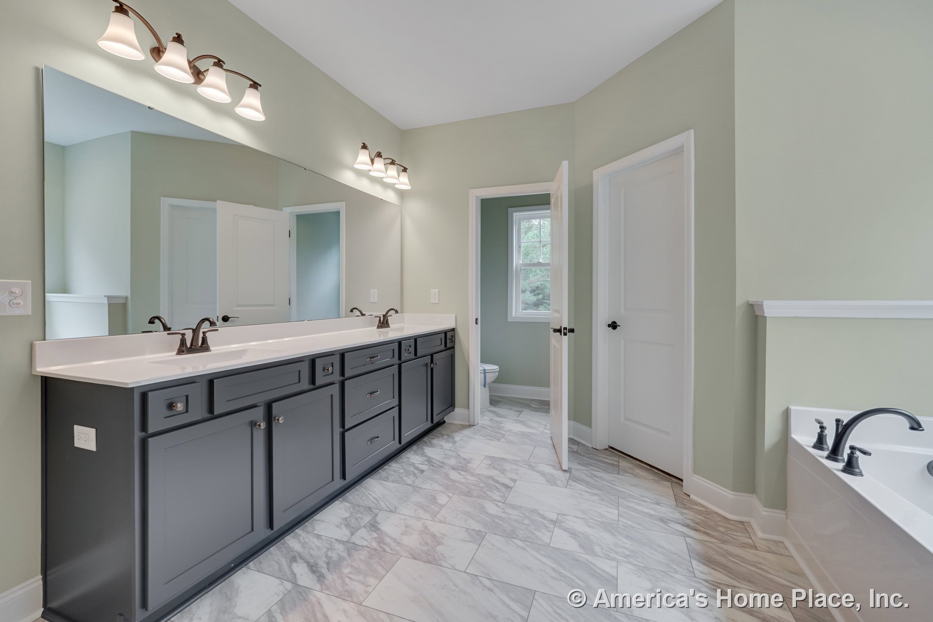 Double vanity with dark cabinetry and undermount sinks, expansive wall mirror, marble-look tile flooring, built-in bathtub with chrome fixtures, recessed lighting, window, white
