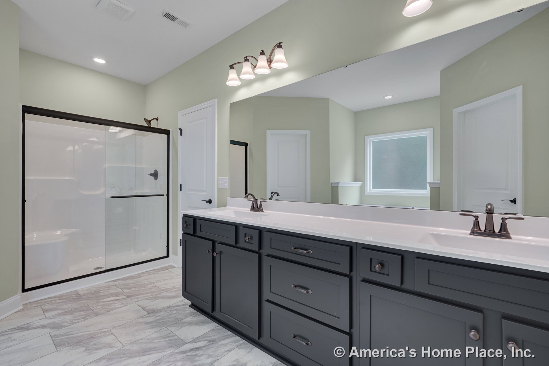Double-sink vanity with dark shaker cabinets, marble-look tile flooring, large wall mirror, glass shower enclosure, built-in overhead lighting, frosted window, and interior door