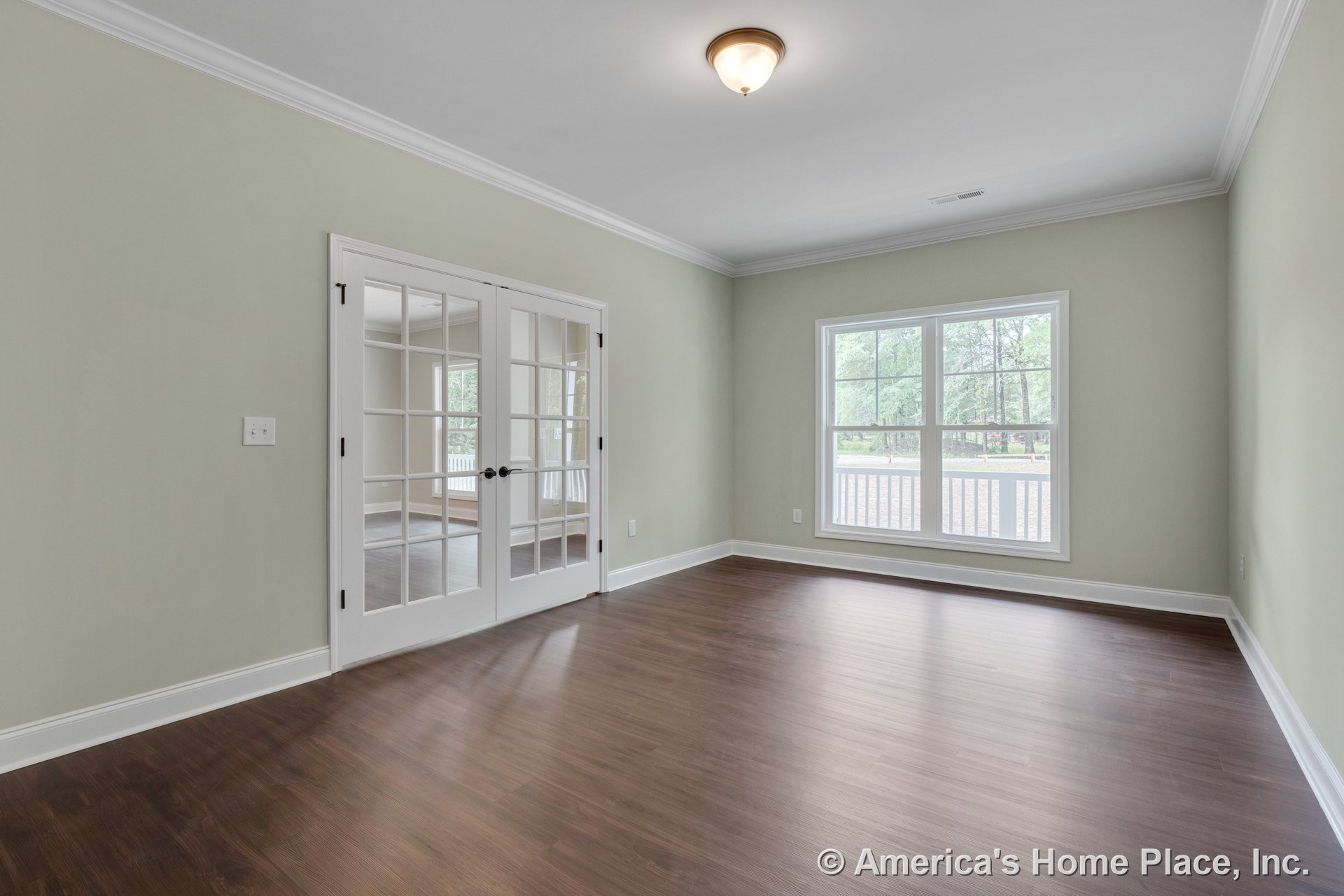 Double French doors and expansive windows with white trim fill the living room with natural light; crown molding, wood-look flooring, neutral walls, ceiling-mounted light fixture