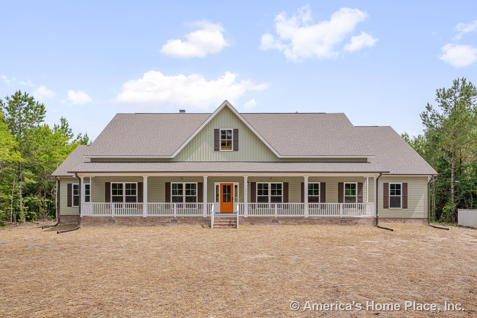 Large covered front porch with white railings and brick foundation, multiple double-hung windows, gabled roof, orange front door, white trim, siding, columns, shutters, and front