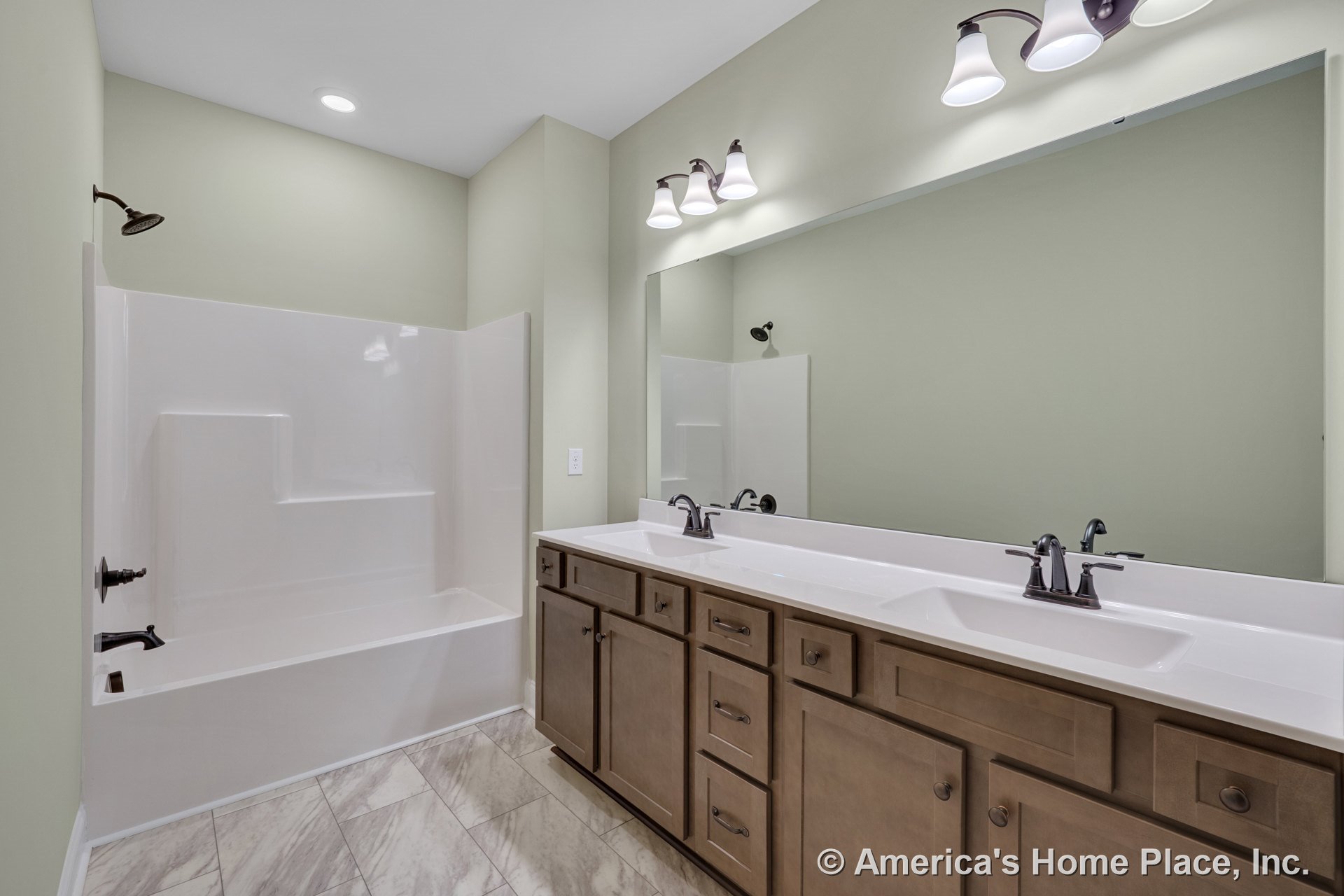 Double-sink vanity with wood cabinetry and stone countertop, large wall mirror above, built-in tub shower with tile surround, tile flooring, overhead and vanity lighting, neutral