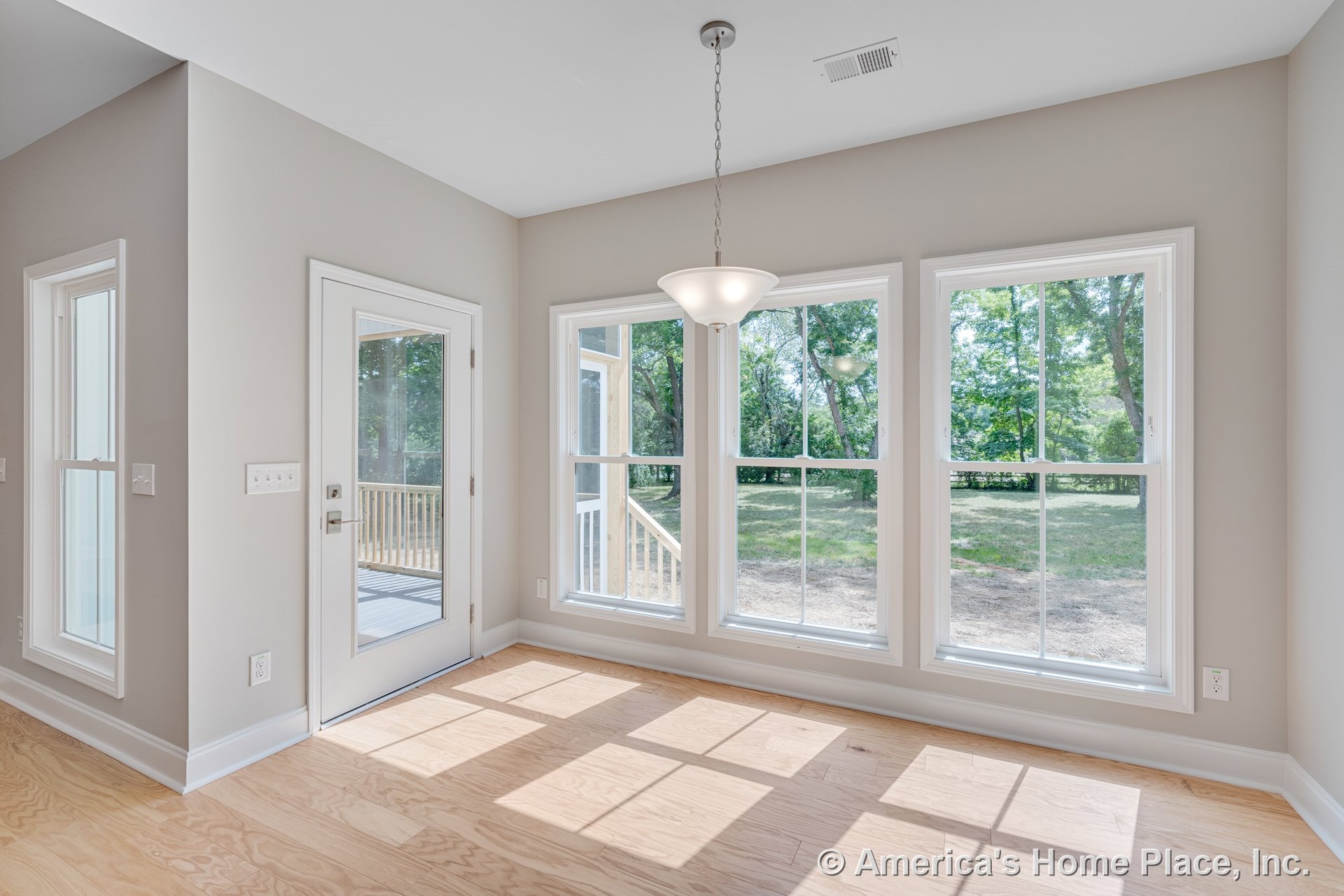 Breakfast nook with double-hung windows, glass door leading to porch, light wood flooring, pendant ceiling light, white trim, neutral wall color, and ceiling vent.