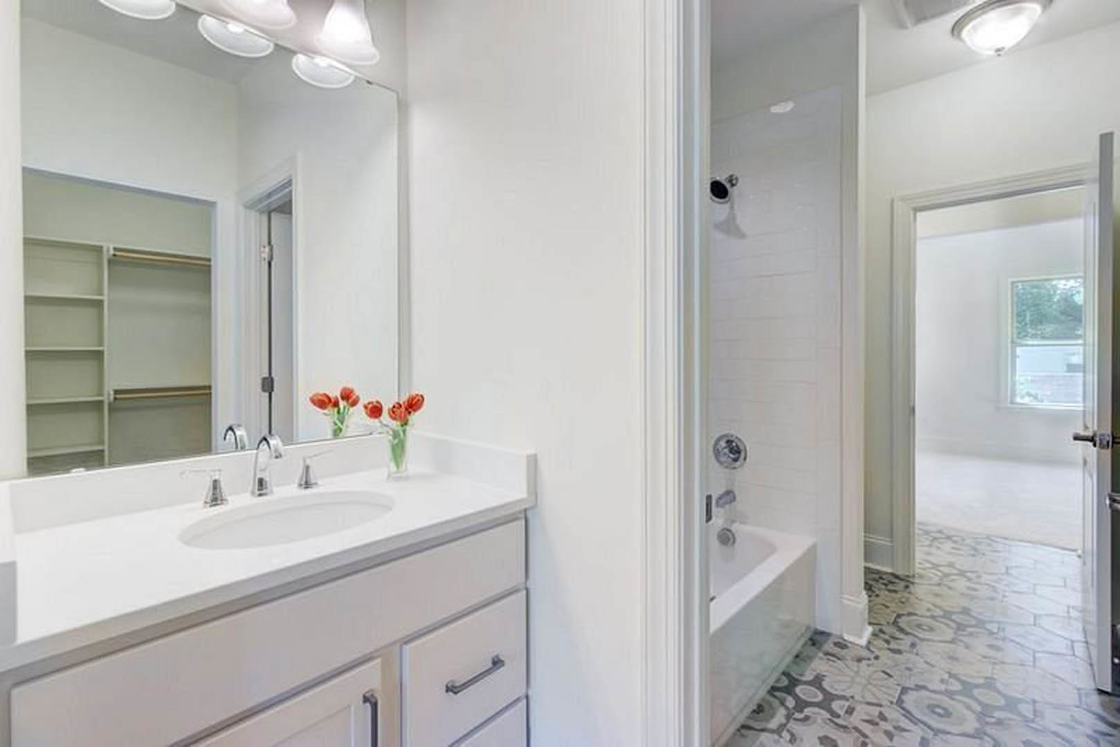 Modern bathroom featuring a freestanding bathtub, white ceramic sink on a stone countertop, tiled walls, chrome faucet, and ceiling light fixture