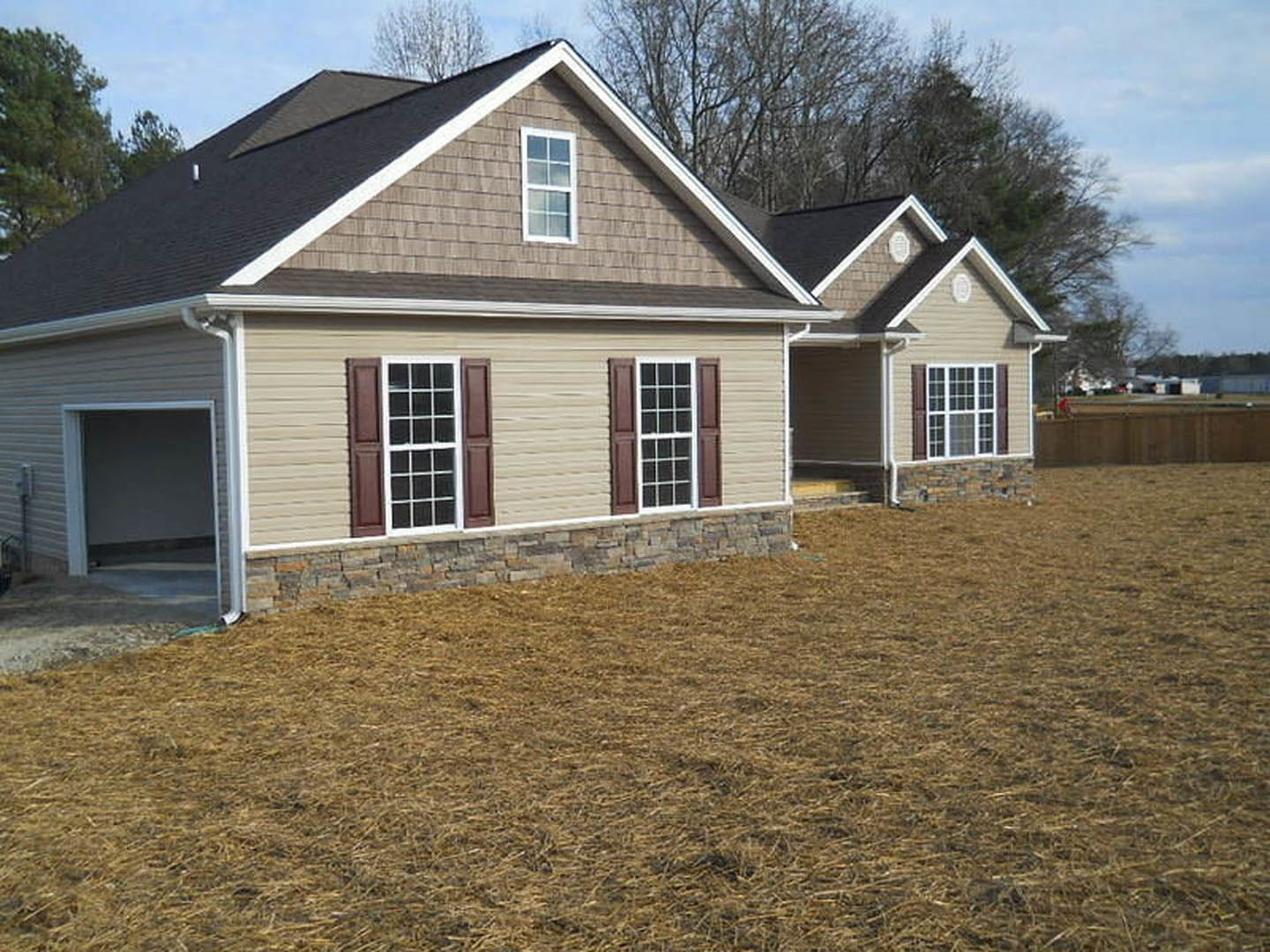 Two-story house with white siding, attached garage, multiple white-framed windows, and manicured grass lawn