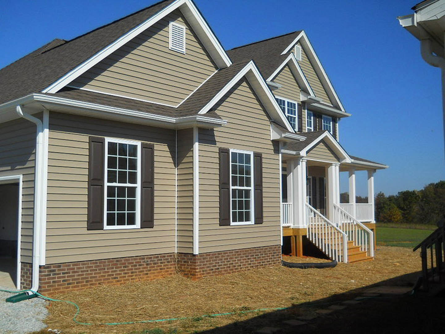 Two-story cottage with light siding, covered front porch, white framed windows, and white staircase leading to entrance.