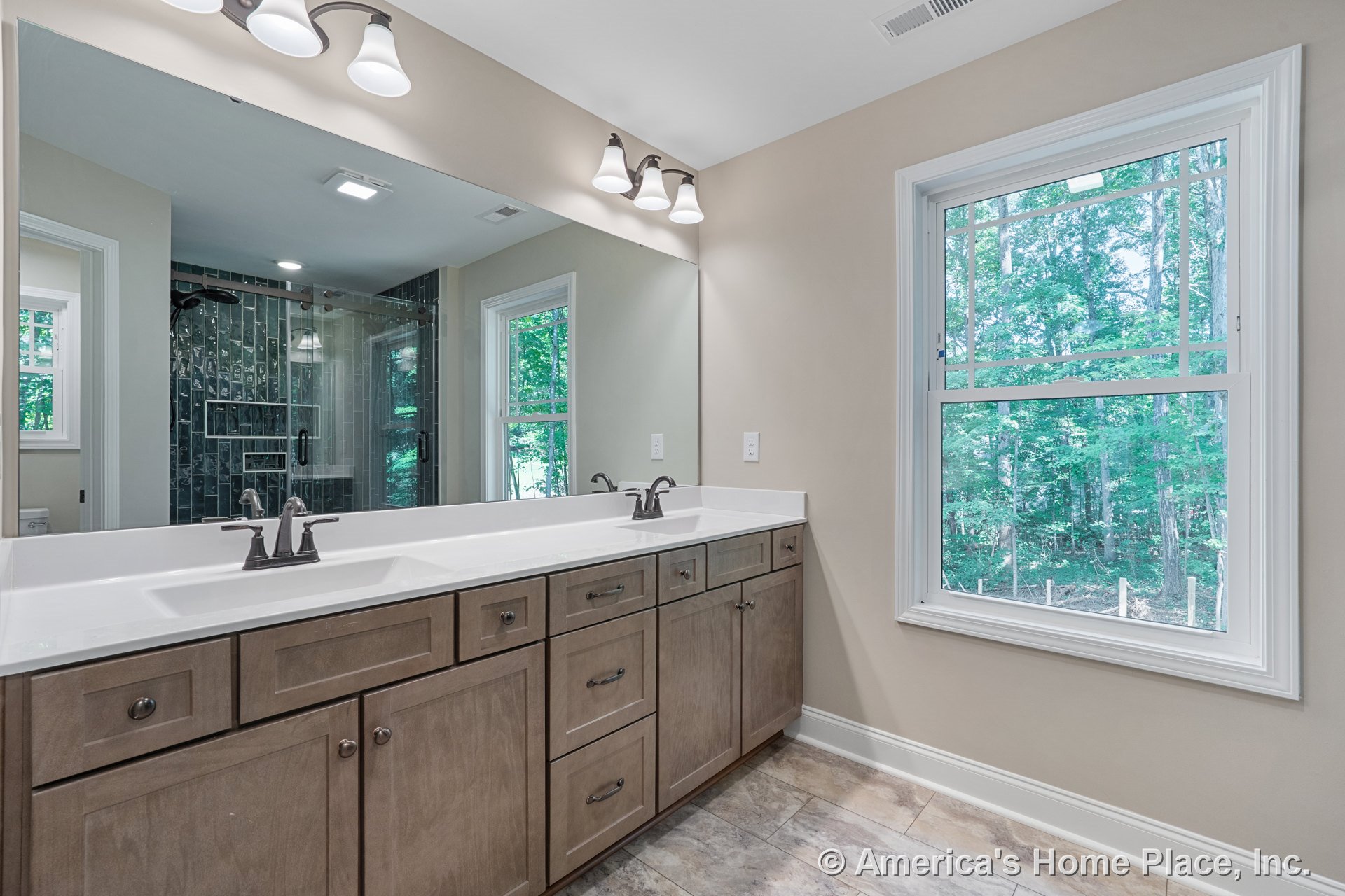 Double vanity with wood cabinetry and quartz countertop, expansive wall mirror above, tile flooring, window with trim, built-in lighting, glass shower enclosure, neutral wall