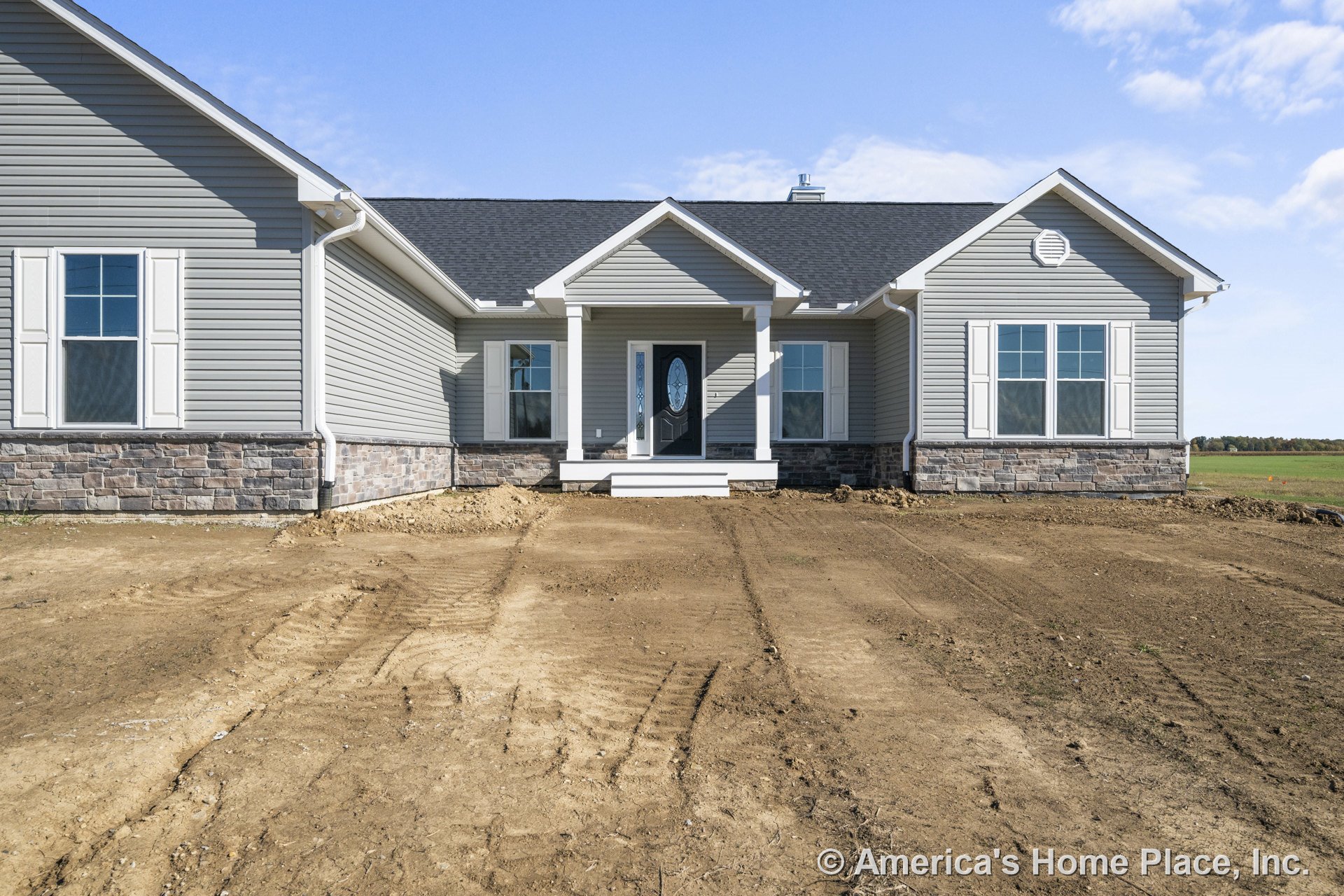 Gray vinyl siding and stone veneer foundation with double-hung windows featuring white trim, covered entry porch supported by white columns, black shingle roof, and ranch-style new