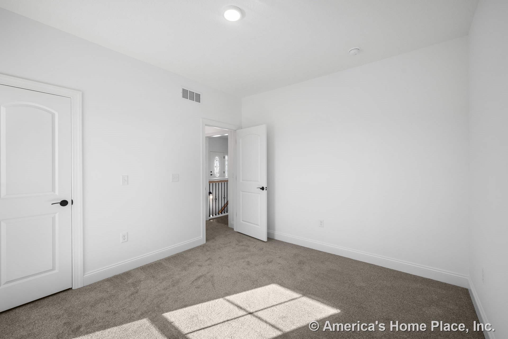 Bedroom with neutral carpet flooring, white paneled doors, white trim and baseboards, recessed ceiling light, window allowing natural light, and soft neutral wall color.