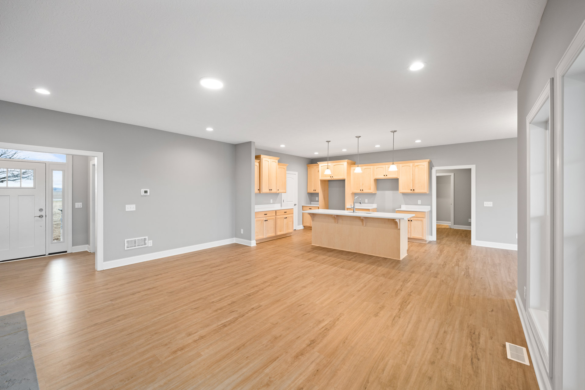 Open-concept kitchen with a central island, wood flooring, white cabinetry, stainless steel faucet, and a white door with glass window.