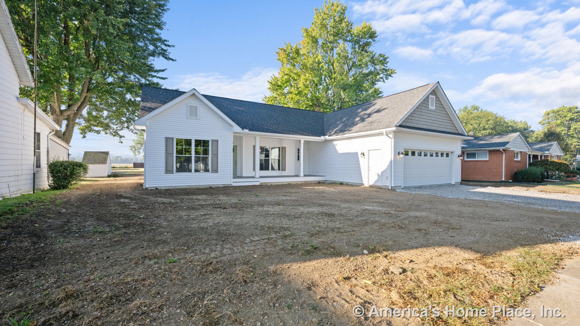 White horizontal siding exterior with large front windows, covered porch supported by columns, attached two-car garage, gray shingle roof, wall-mounted exterior lighting, vented