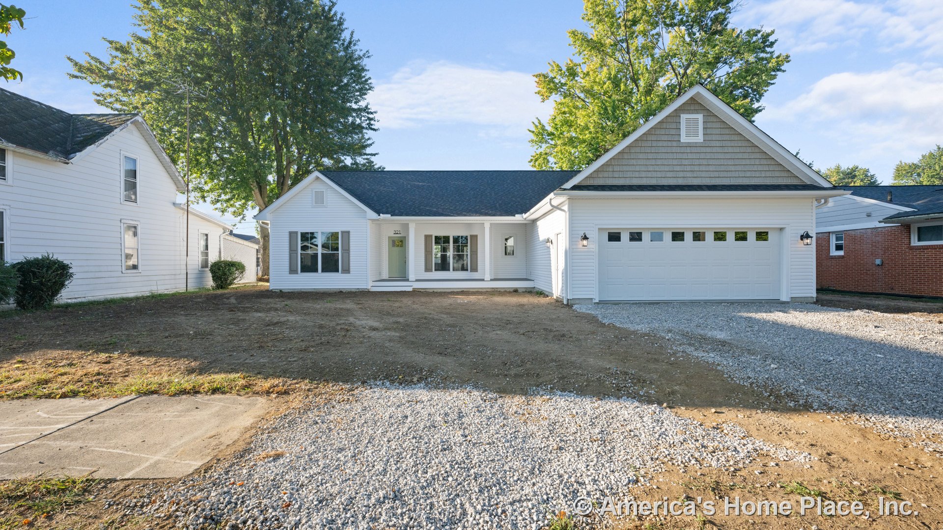 White horizontal siding exterior with gable roof, covered front porch, attached two-car garage featuring windows, large front windows, exterior wall lanterns, and driveway leading