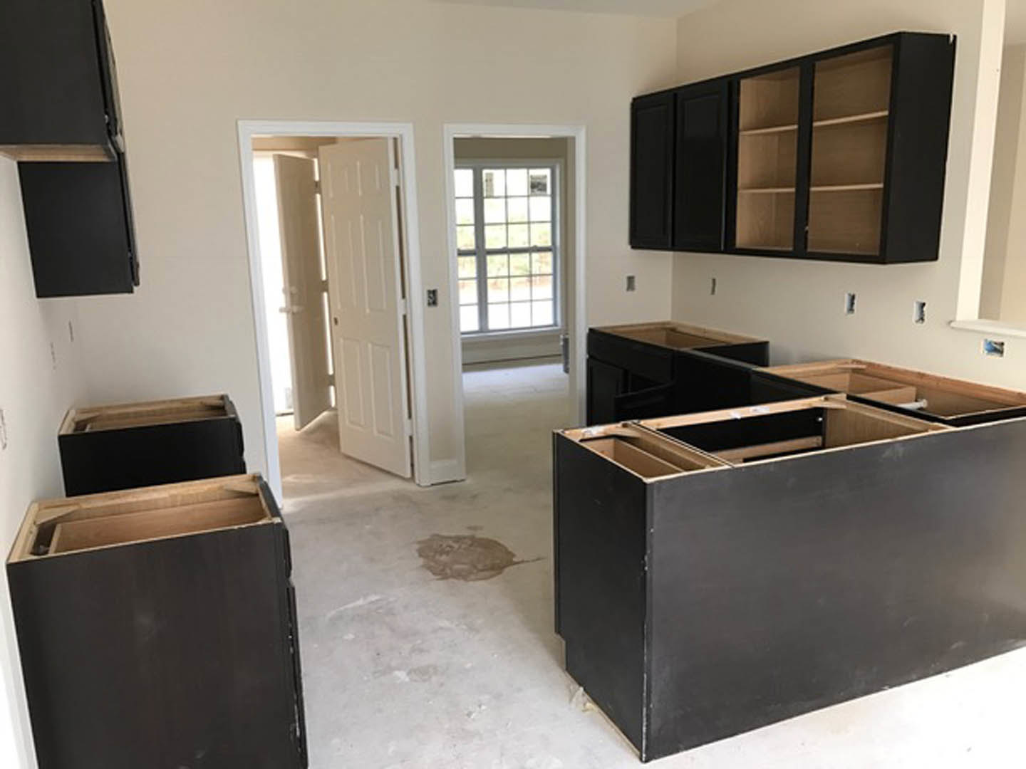 Kitchen with matte black cabinets, black drawers, wooden countertop, white door with natural light, and open shelving