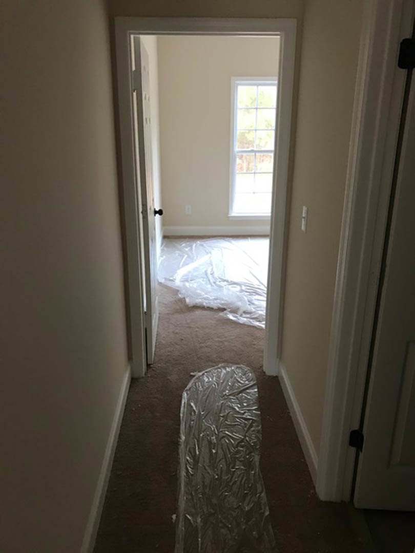 Plastic bag with a pattern resting on light flooring near a white-framed window, white wall, and door in a remodeled interior space
