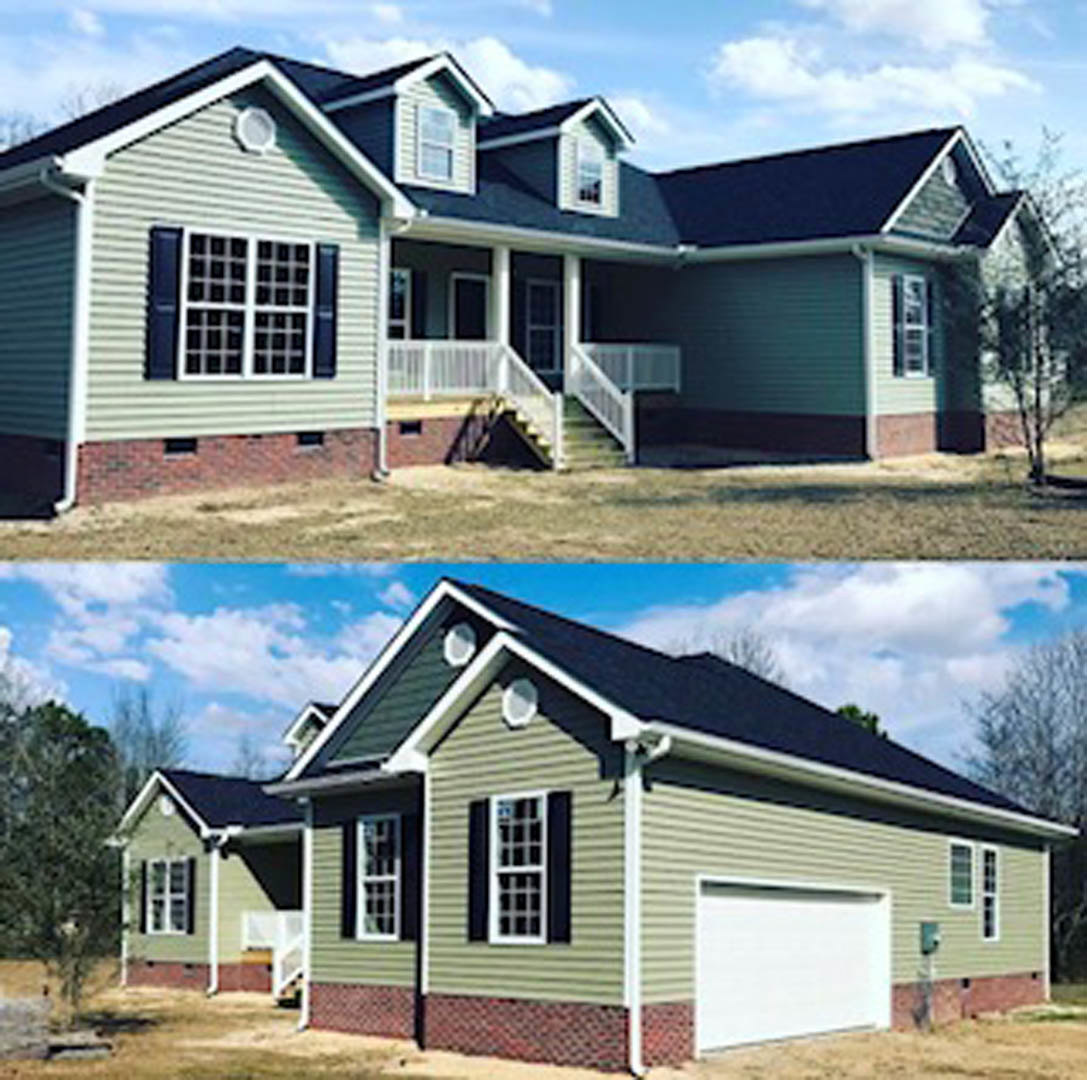 Two-car garage with white doors and green entry door, front porch with stairs, white fence and railing, light siding, multiple windows, trees in background