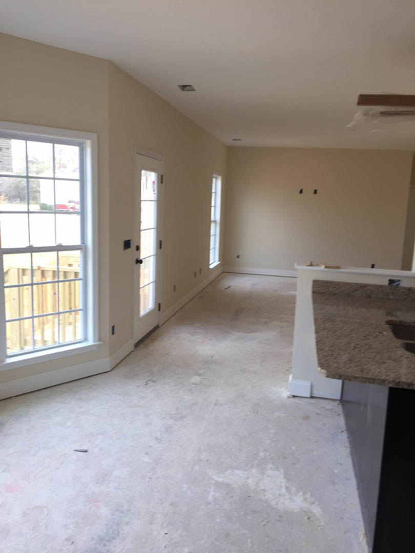 Open-concept kitchen with white flooring, modern cabinetry, stainless steel sink, stone countertop, large window overlooking nearby building