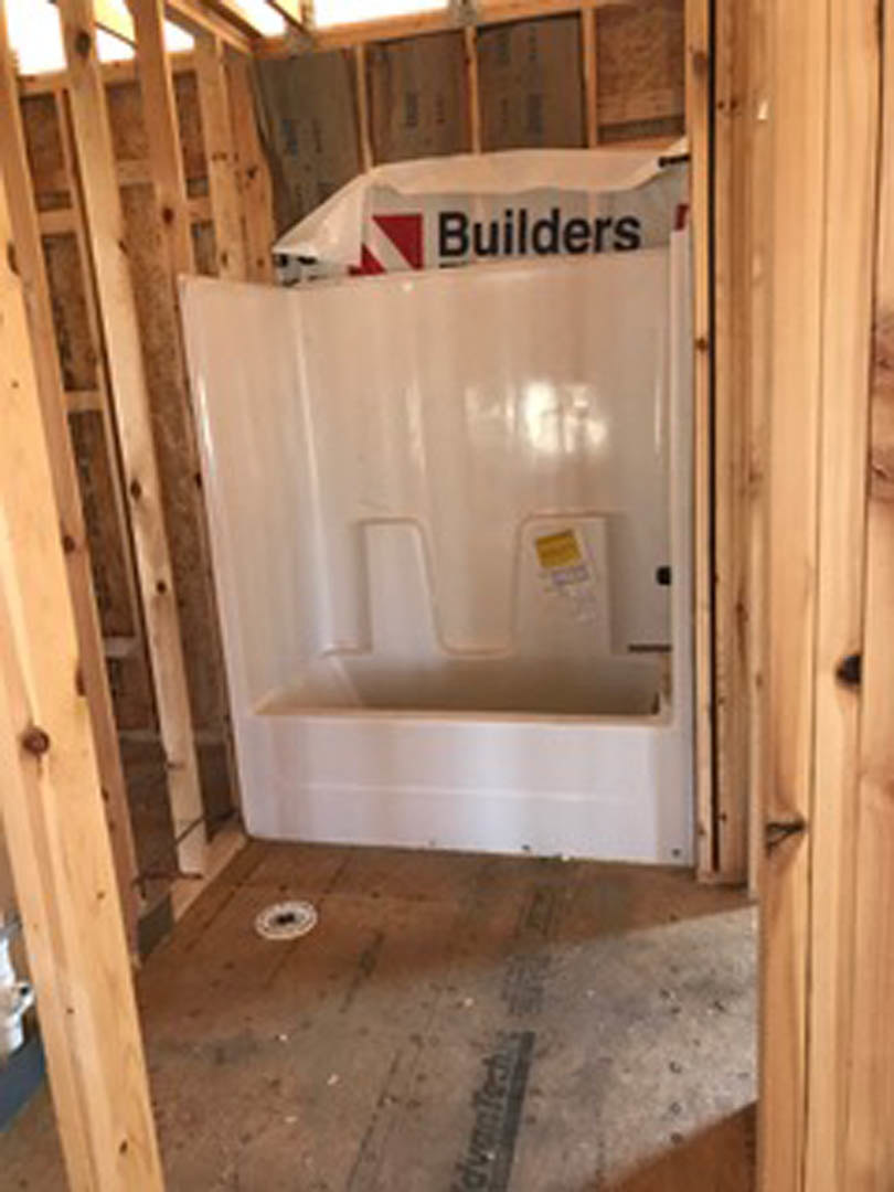 White tile shower stall with glass door, chrome fixtures, and wood trim in a modern bathroom