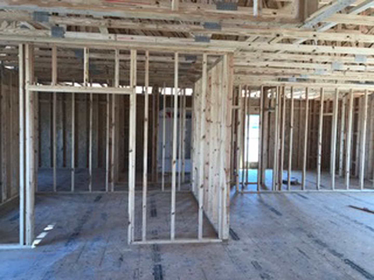 Room under construction with exposed wood framing, beams, and insulation visible on walls and ceiling