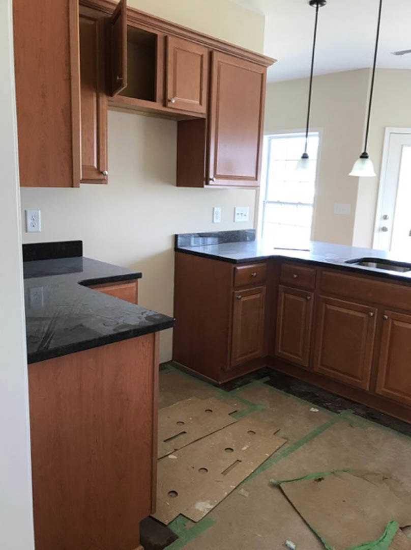 Kitchen with matte black countertops, white cabinetry, stainless steel sink, and modern appliances