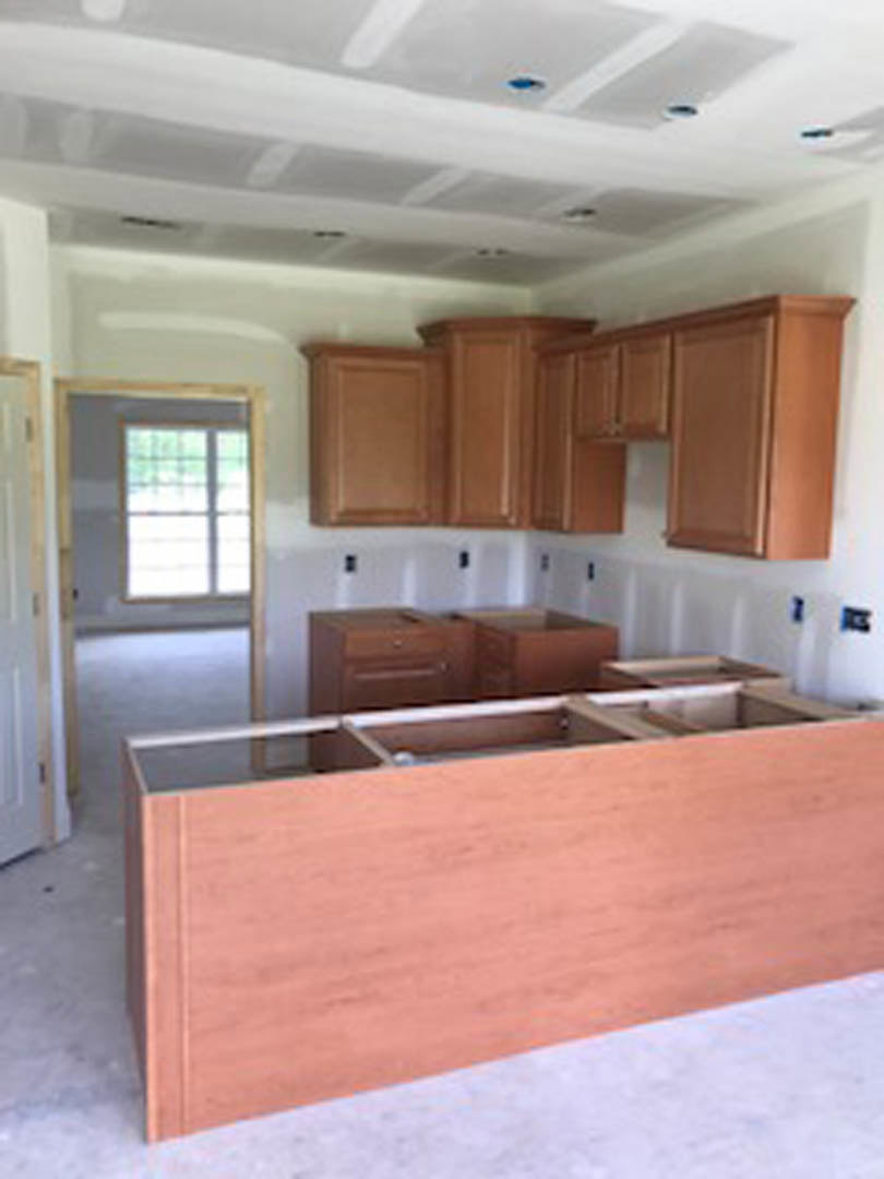 Kitchen with natural wood cabinets, stone countertop, stainless steel sink, and a wooden door leading to another room