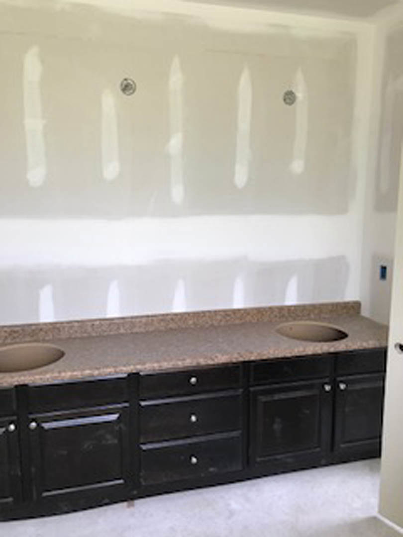 Granite countertop with undermount sink, chrome faucet, white tile backsplash, and wood cabinetry in a modern bathroom