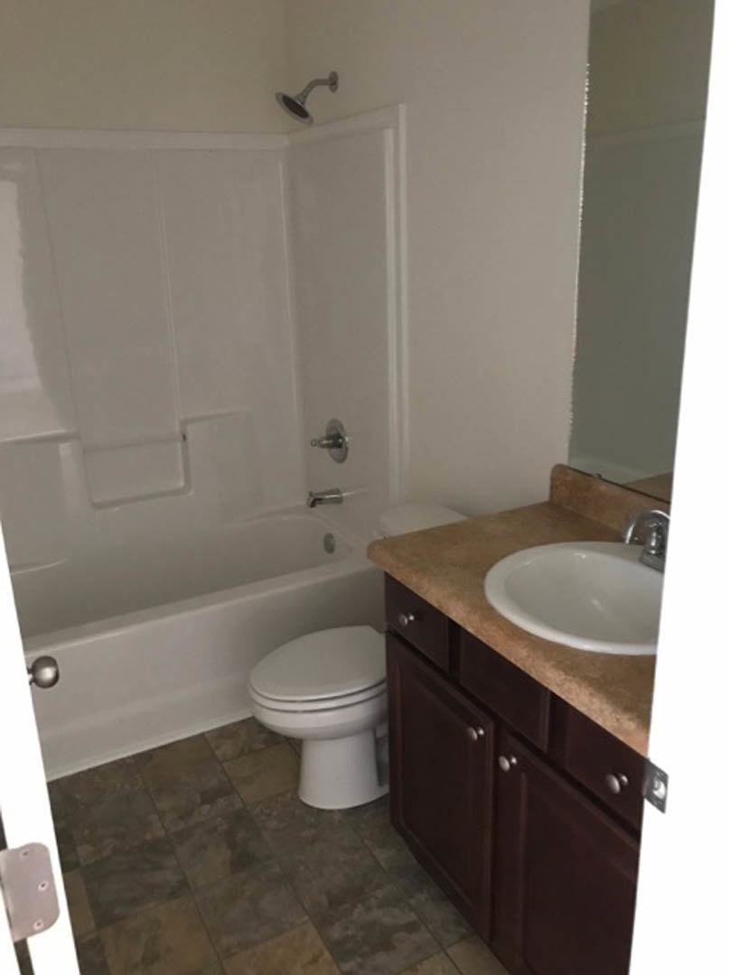 Modern bathroom featuring white ceramic sink with chrome faucet, adjacent toilet, freestanding bathtub, tiled walls, and black shower head.