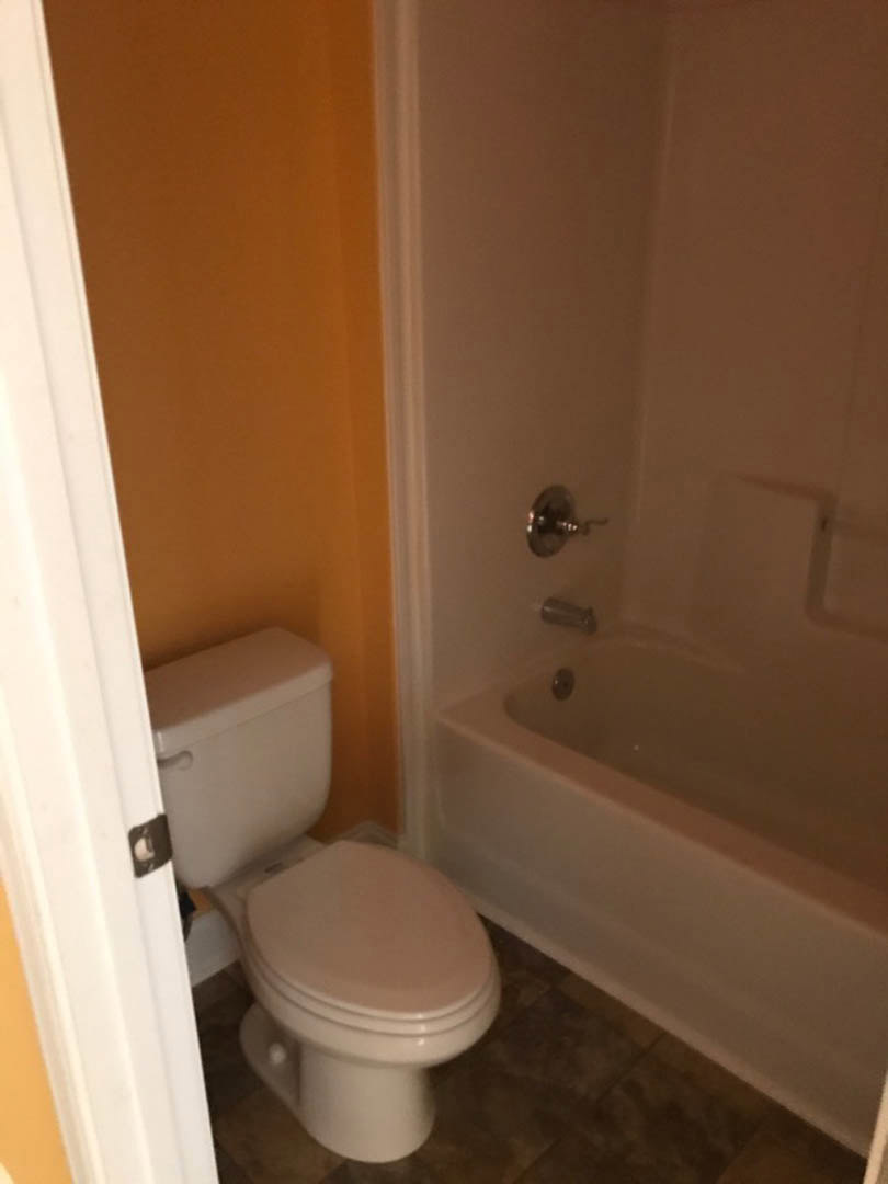 White bathtub and toilet with chrome fixtures in a tiled bathroom, neutral walls, and recessed lighting