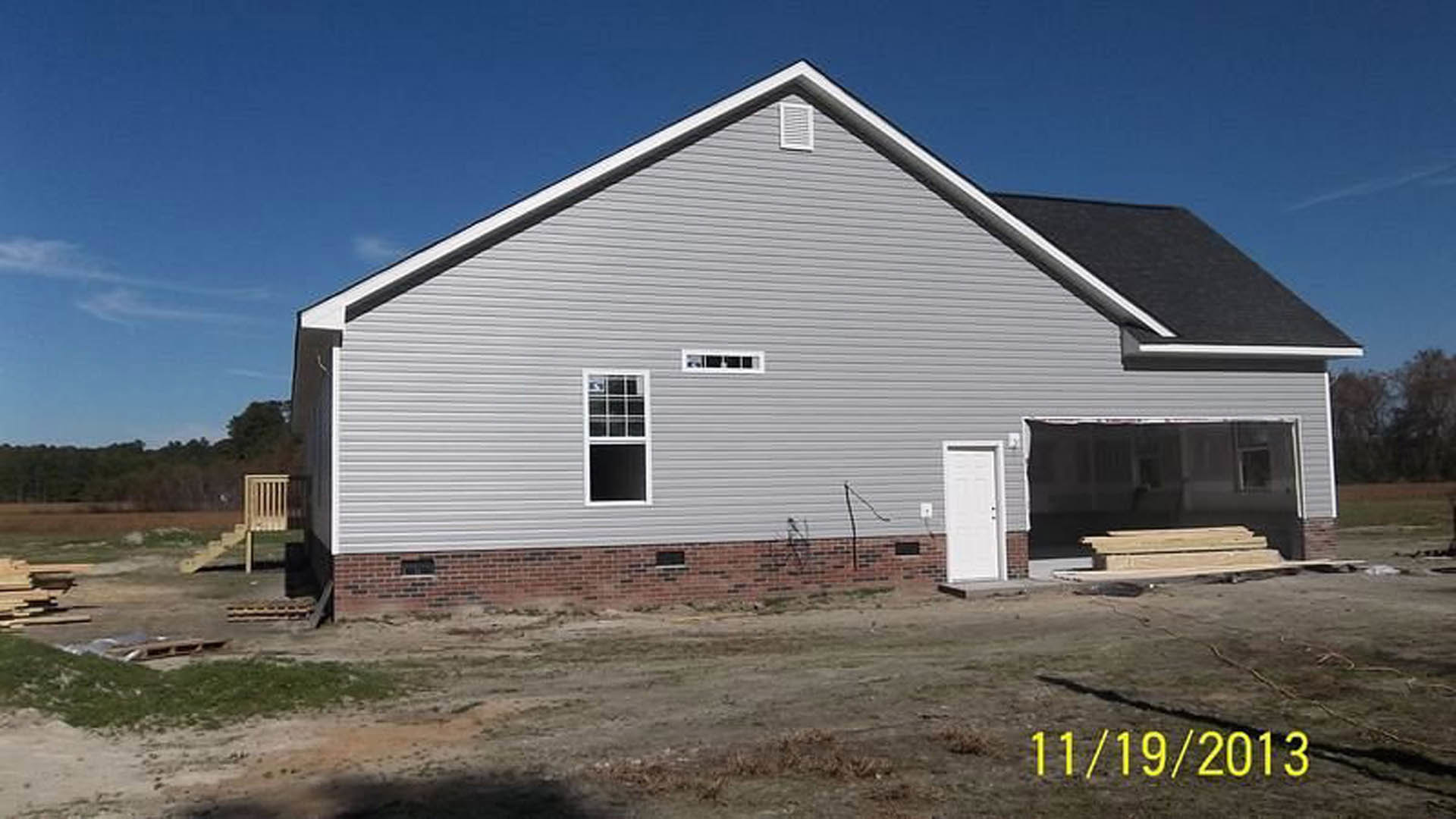Two-story home with attached garage, white siding, white-framed windows, and white vent; yellow house numbers on black plaque near entry; Rockingham Meeting House visible in