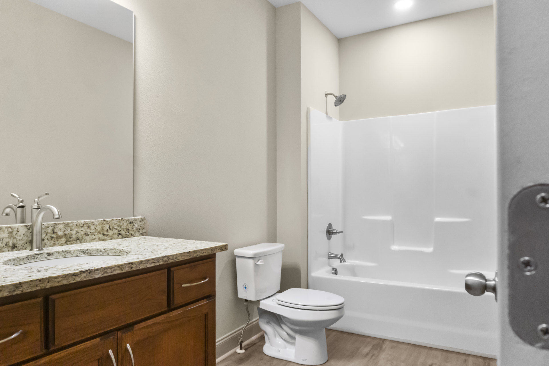 White toilet with closed lid beside glass-enclosed shower, light gray tile flooring, and white walls