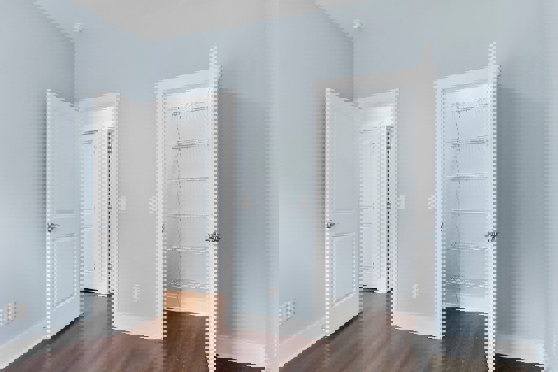 White doors with silver handles, built-in white shelves, white walls with a light switch, wooden flooring with white trim