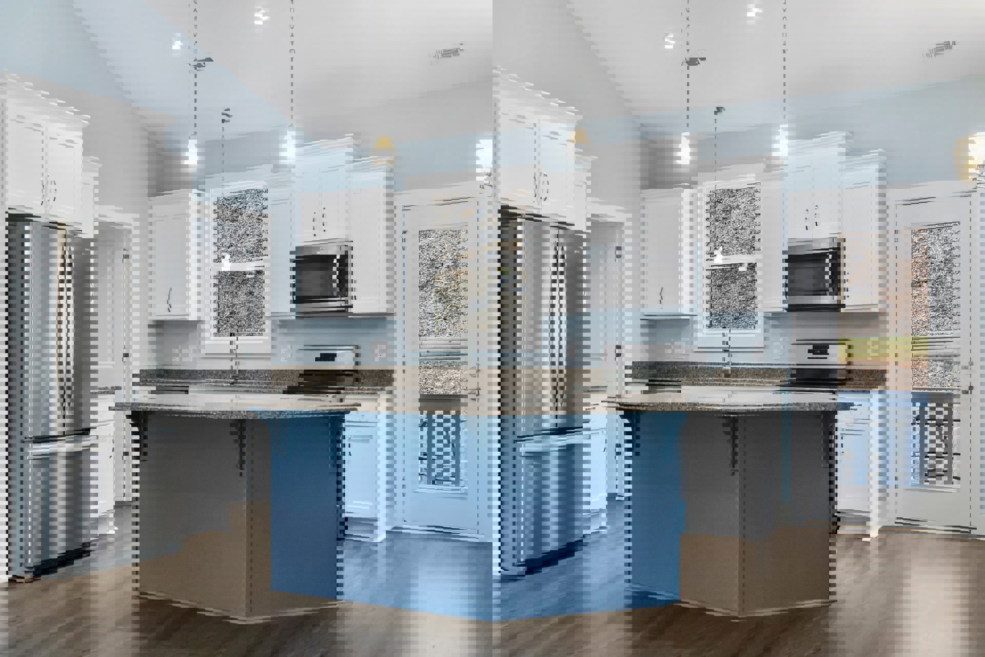 Blue kitchen island with white quartz countertop, stainless refrigerator, built-in microwave, glass-paneled door, white cabinetry, recessed ceiling lights, and vent.