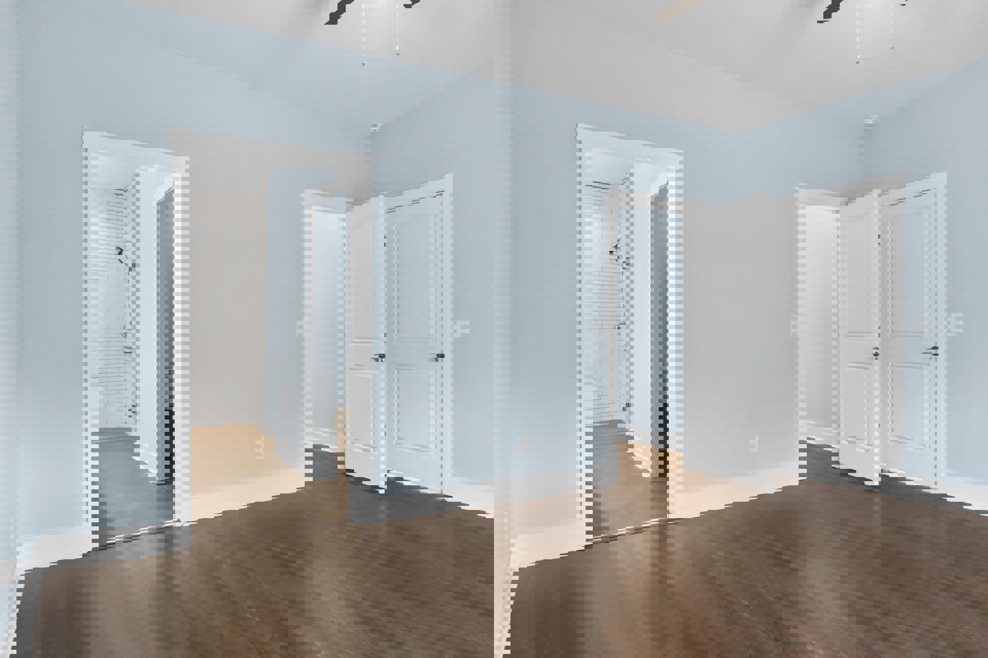 White paneled doors with black handles set against smooth plaster walls, hardwood flooring with natural wood grain, minimalist interior detailing.