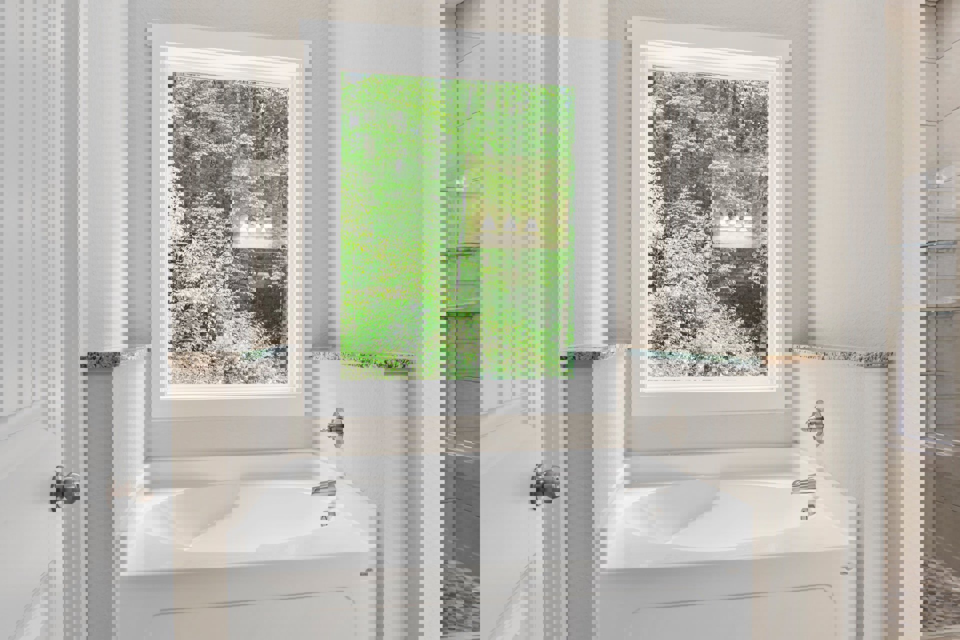 Freestanding white bathtub beneath large window with leafy trees visible outside, light-colored walls, chrome faucet, and smooth tile flooring