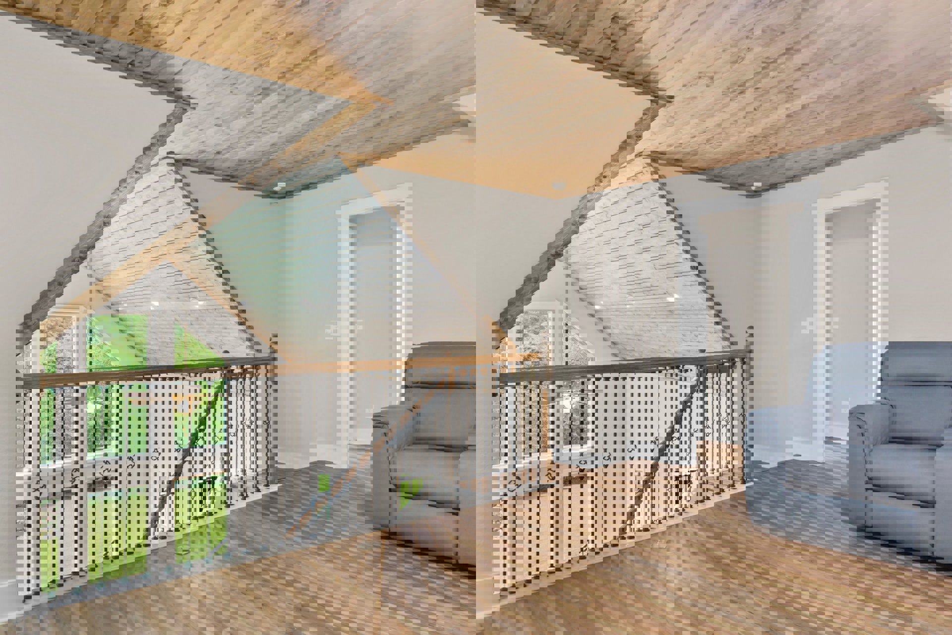 Open living space featuring wood plank flooring, matching wood ceiling with recessed lights, white walls, metal stair railing, modern ceiling fan, large window, and neutral