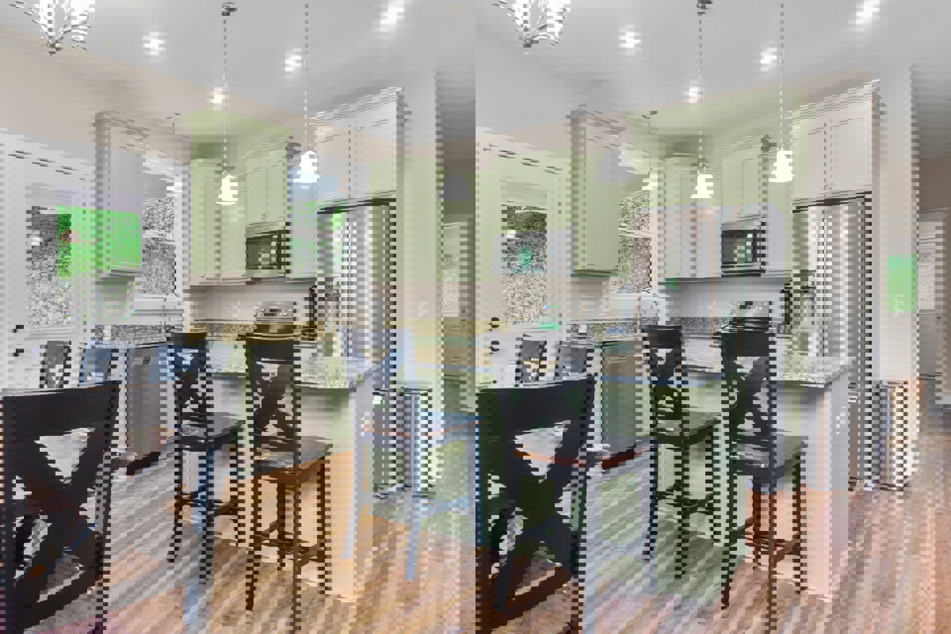 Green shaker cabinets, black dining chairs around a wood table, white quartz countertops, stainless steel microwave, light hardwood floors, and neutral walls in a modern kitchen.