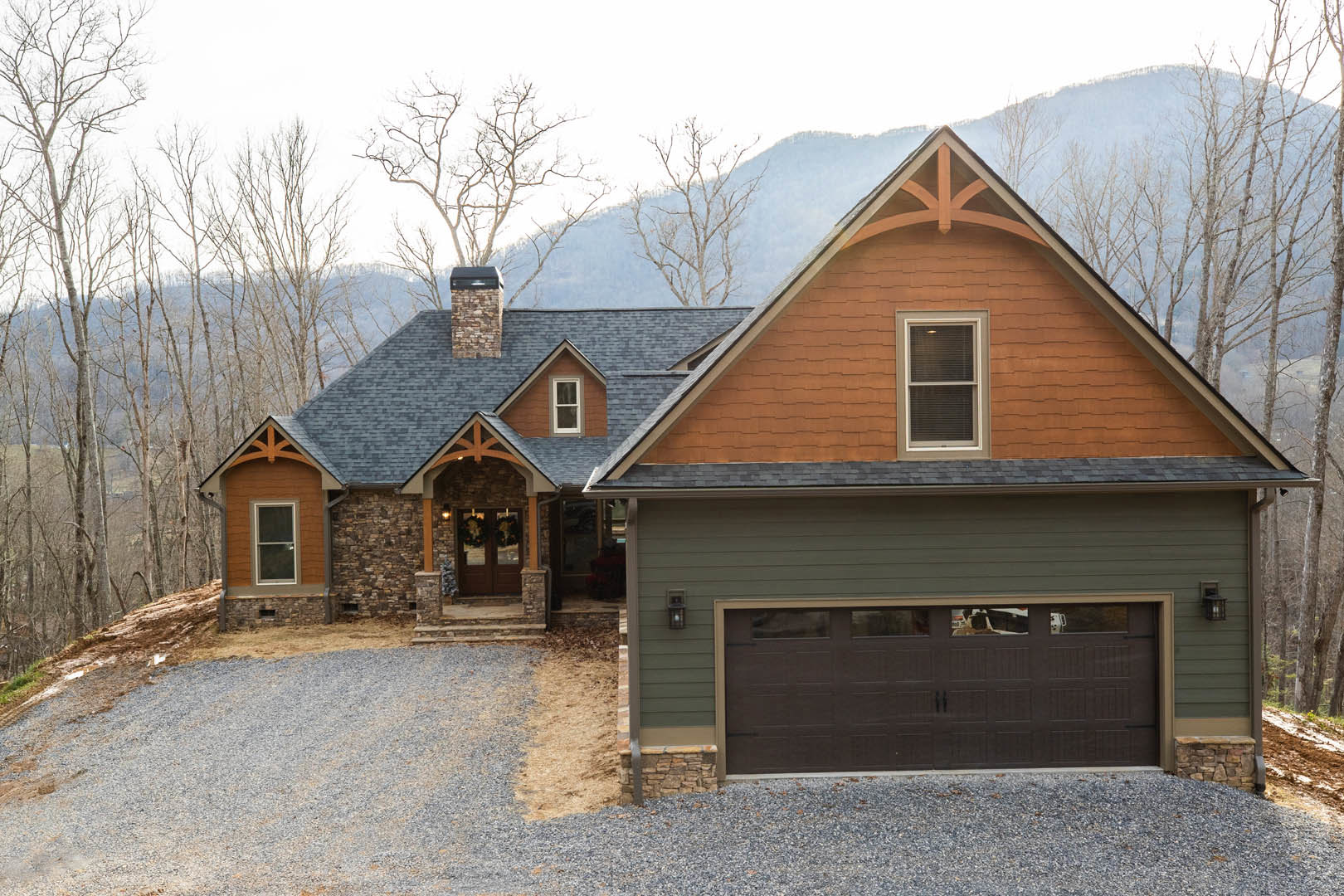Two-story home with brick chimney, black shingle roof, attached garage featuring white paneled door with windows, concrete driveway, white-framed windows with blinds, landscaped