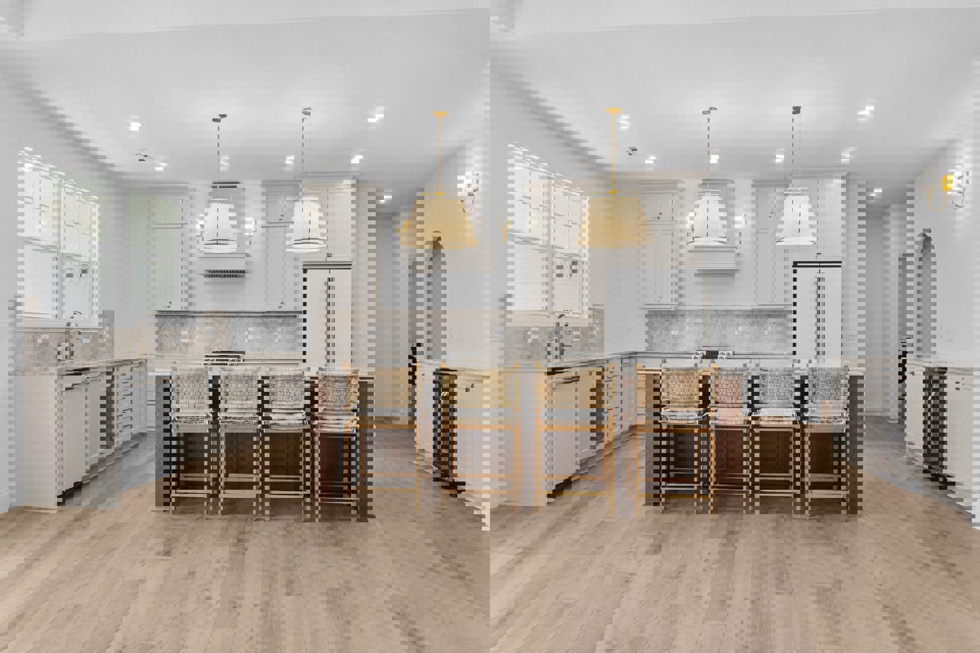 Modern kitchen with white cabinetry, stone countertop bar, two cushioned chairs, stainless steel sink and faucet, pendant light fixture, wood flooring