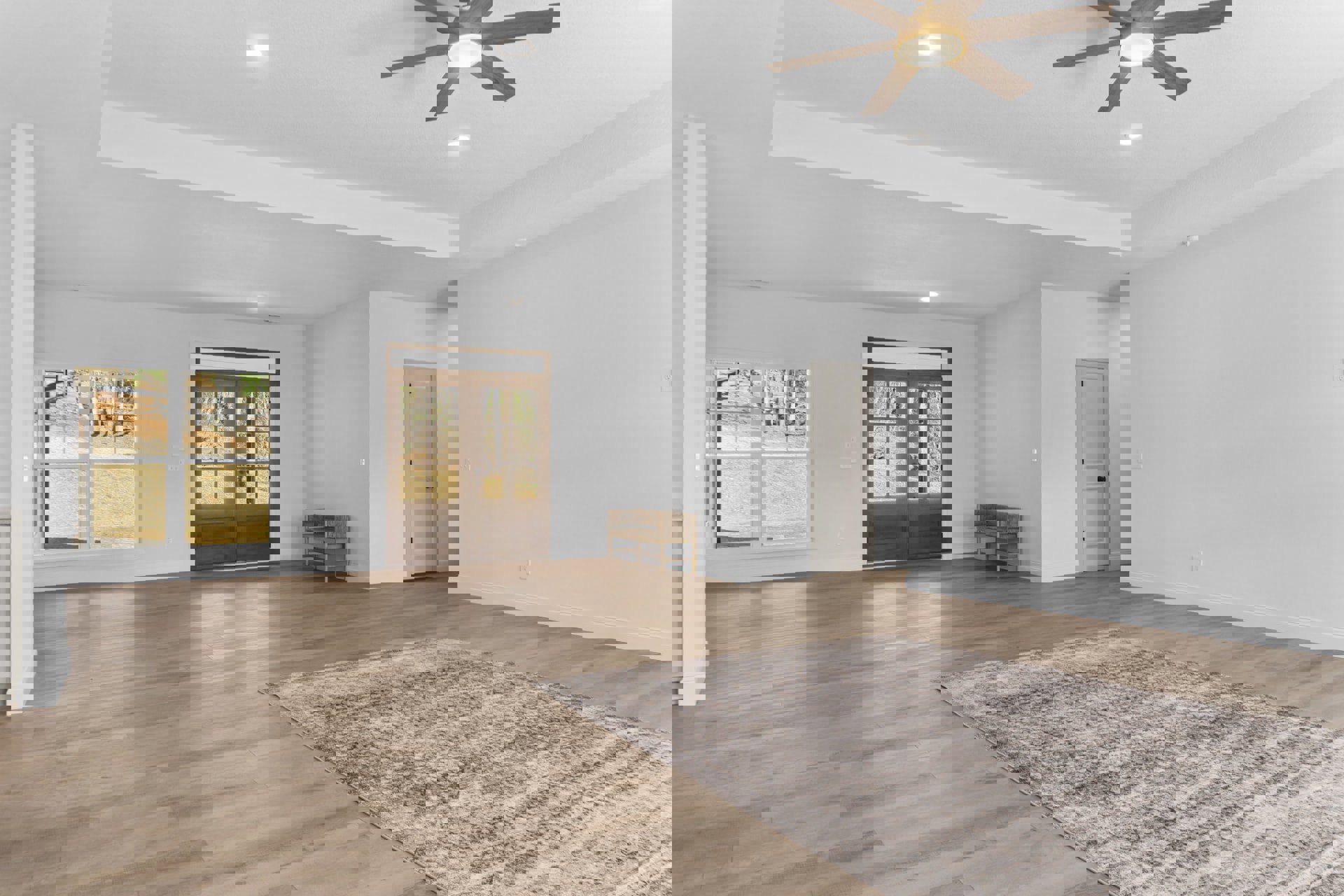 Wood flooring with patterned rug, wooden bench with white cushion, double glass-paneled doors, white door with black knobs, ceiling fan with light fixture, neutral walls.