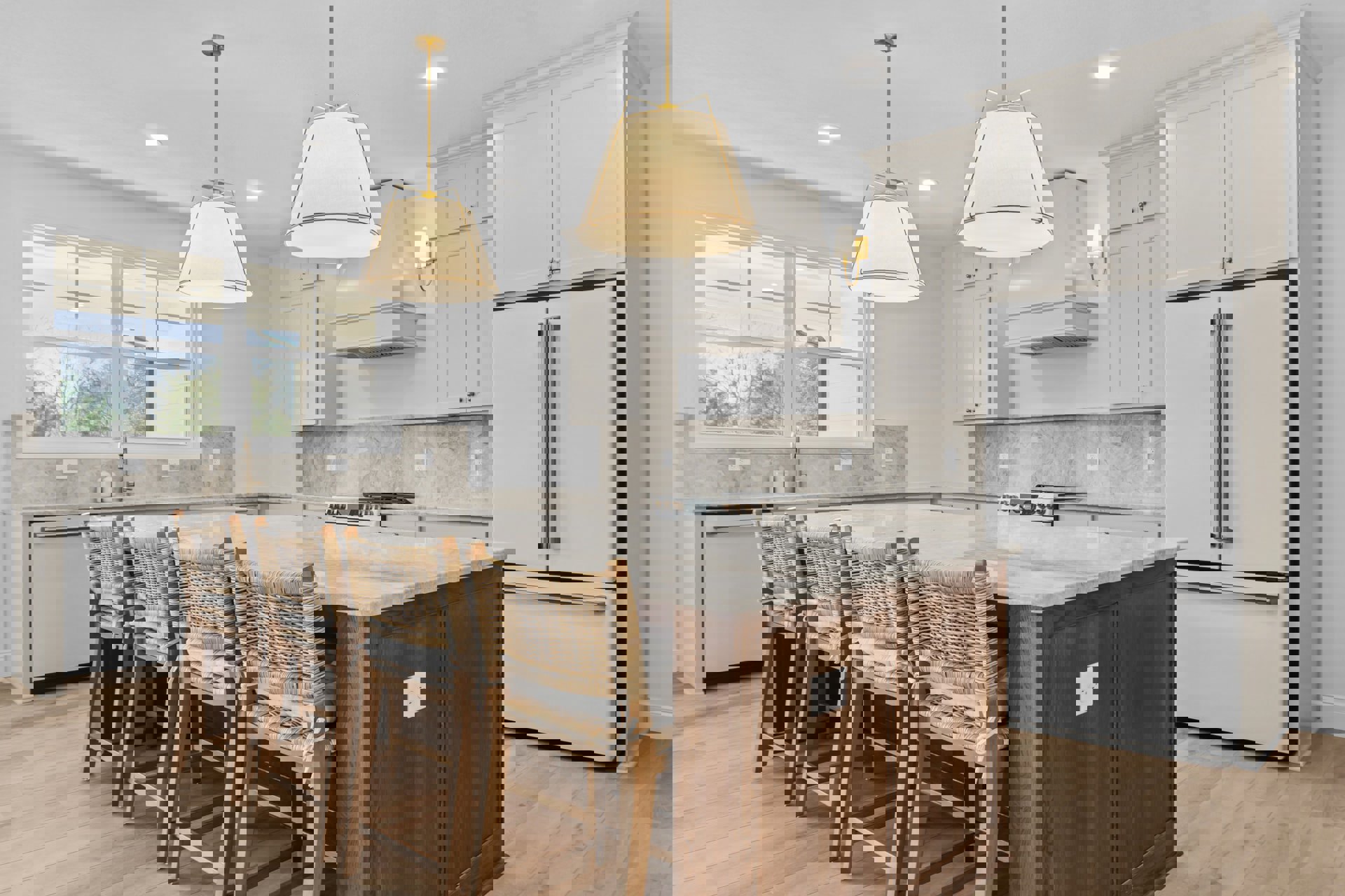 Spacious kitchen featuring a large central island with bar chairs, white cabinetry, stainless steel refrigerator, pendant light fixture, sink beneath windows, and light-colored