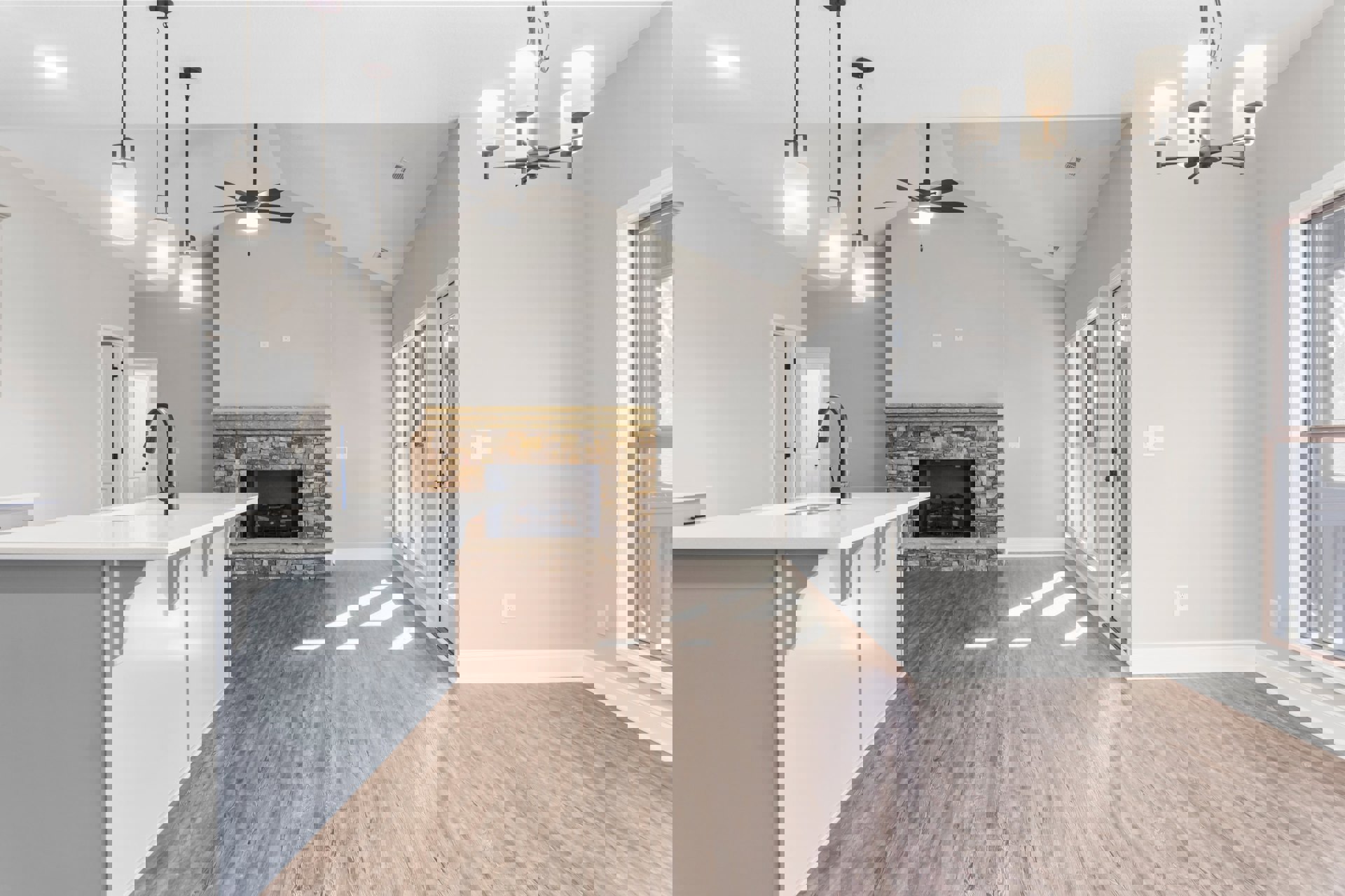 Open-concept kitchen and living room featuring a tile fireplace, white dining table, wall-mounted light fixture, large window, kitchen island with built-in sink, laminate flooring