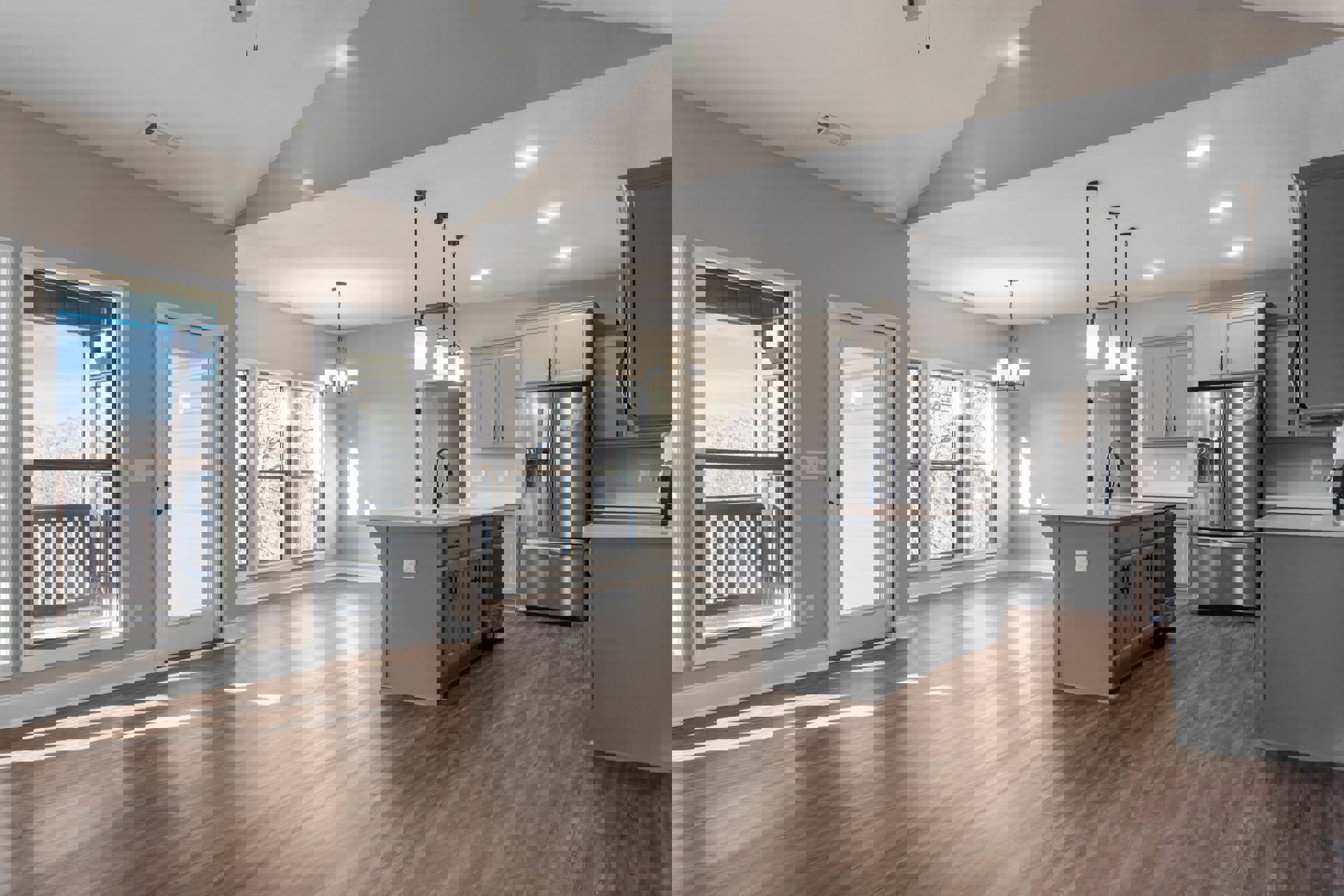 Open kitchen and dining area with wood flooring, stainless steel refrigerator with ice and water dispenser, glass door, large window overlooking trees and sky, grey walls and